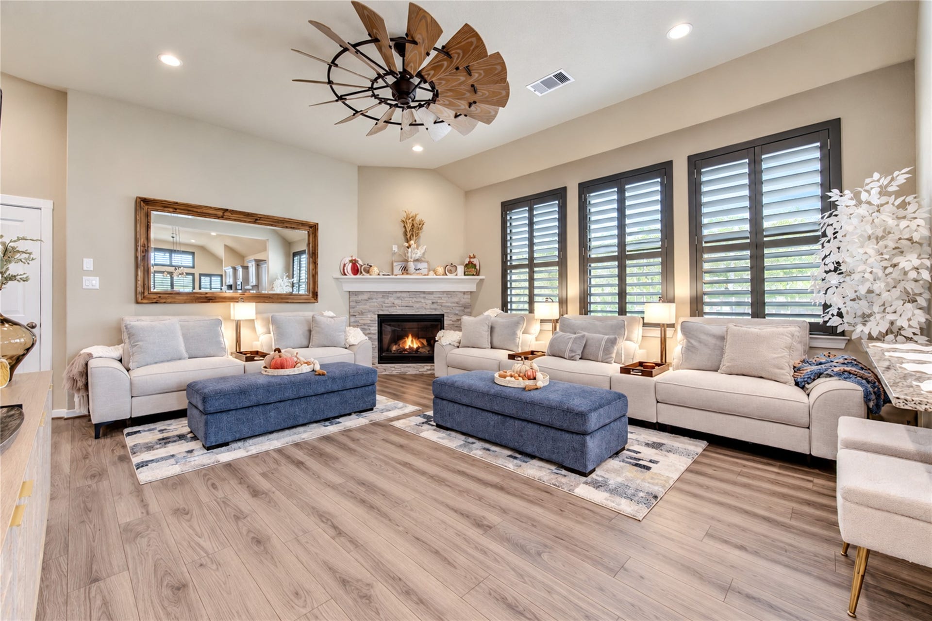 24911 Via Arabella Lane, Richmond, TX 77406 A spacious family room featuring high ceilings, a stone-accented fireplace, plantation shutters and beautiful wood-look tile flooring.