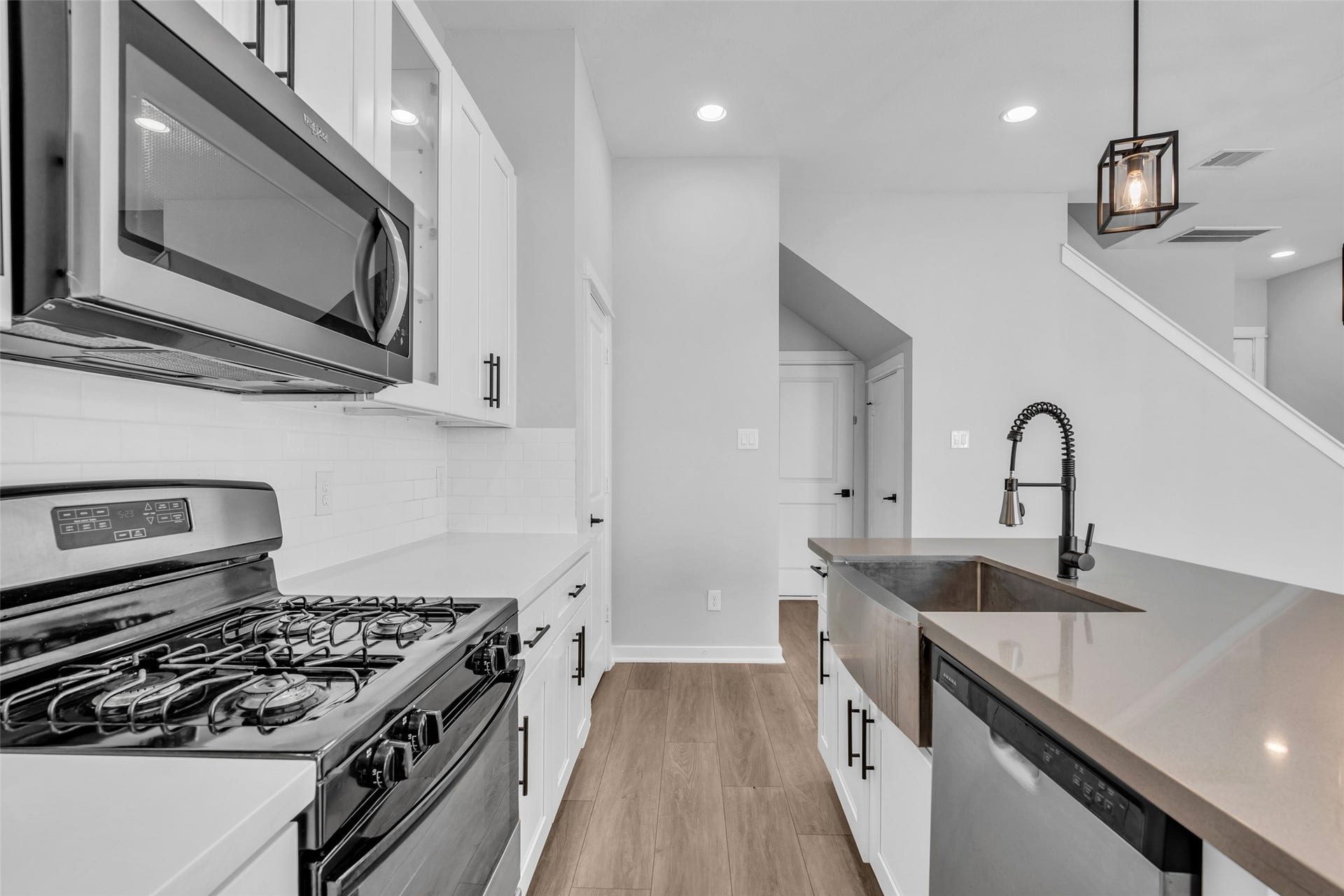 8474 Berry Green Lane, Houston, TX 77022 Cook on a gas range with an over-the-range microwave and cabinetry close at hand.