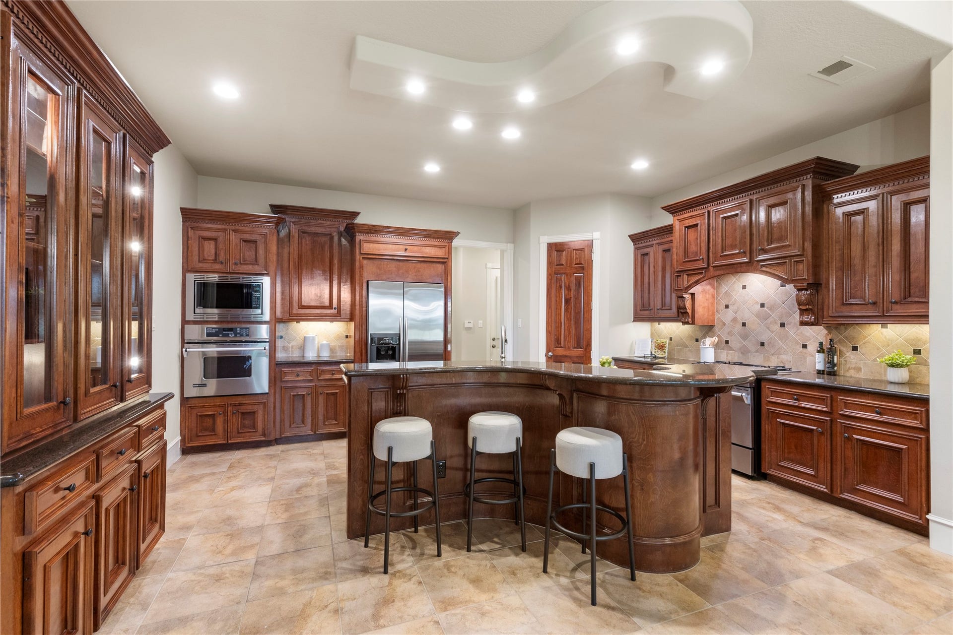 6207 Windrose Hollow Lane, Spring, TX 77379 The kitchen offers a generous island, rich cabinetry, and an open connection to the breakfast area and den. The original custom design includes a distinctive piano shaped island, adding personality and function.