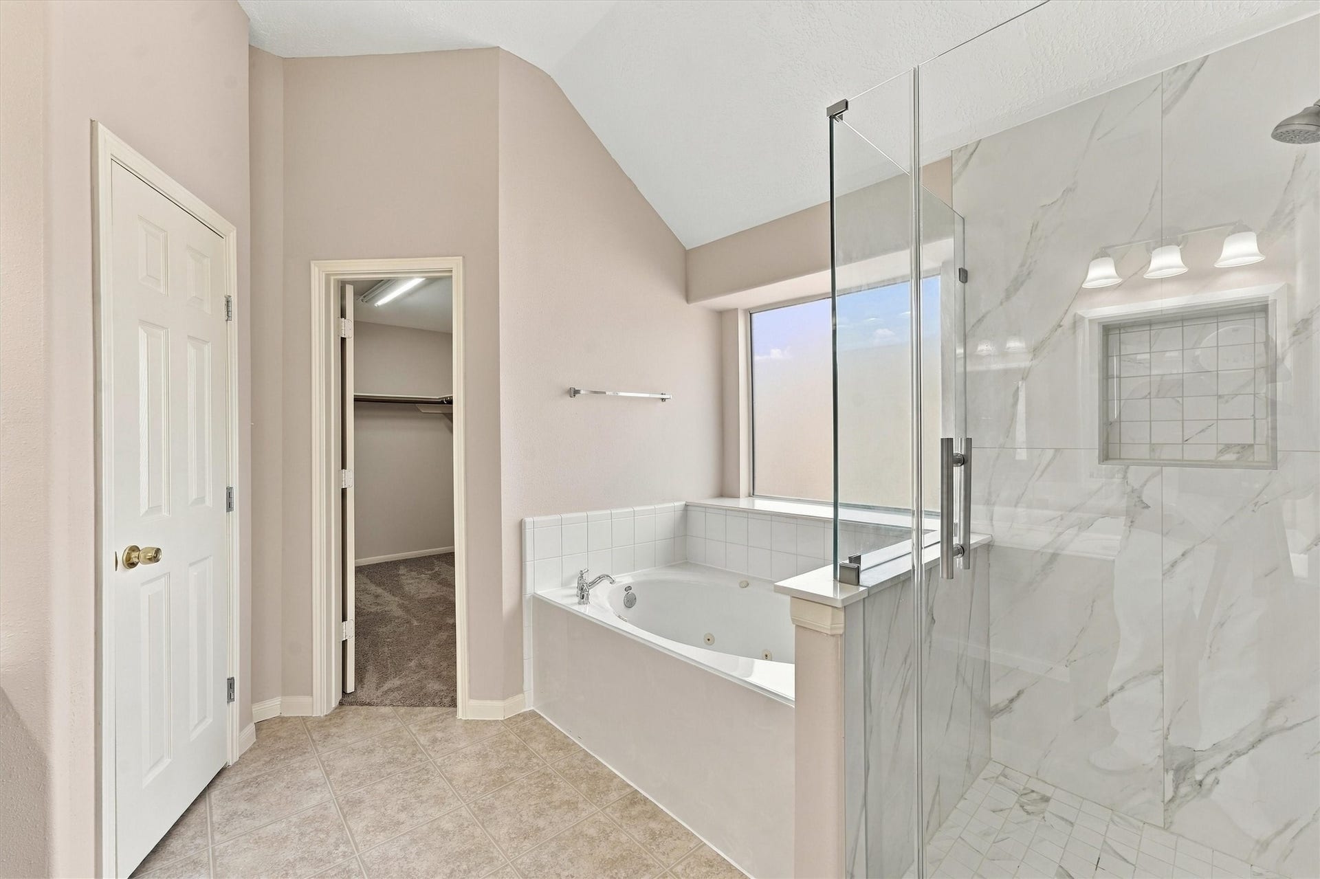Indulge in the luxury of a primary bathroom featuring an updated walk-in shower and a relaxing soaking tub, perfect for unwinding.