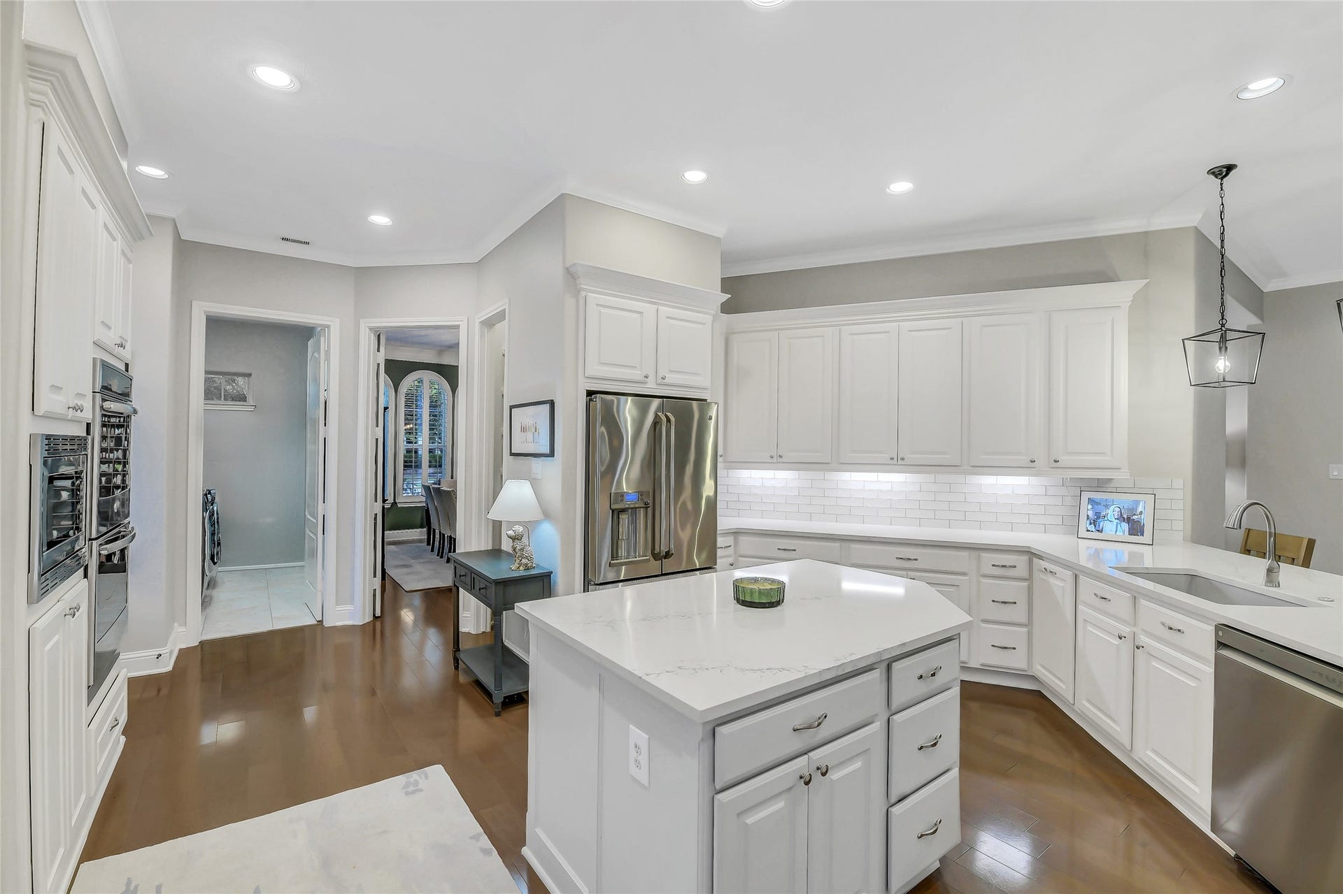 5410 Briarcliff Lane, Fulshear, TX 77441 This bright, open-concept kitchen features an oversized quartz island, abundant custom cabinetry, stainless steel appliances, and a timeless white subway tile backsplash. Designed for both everyday living and entertaining, the spacious layout offers ample prep space, generous storage, and seamless flow into the surrounding living areas.