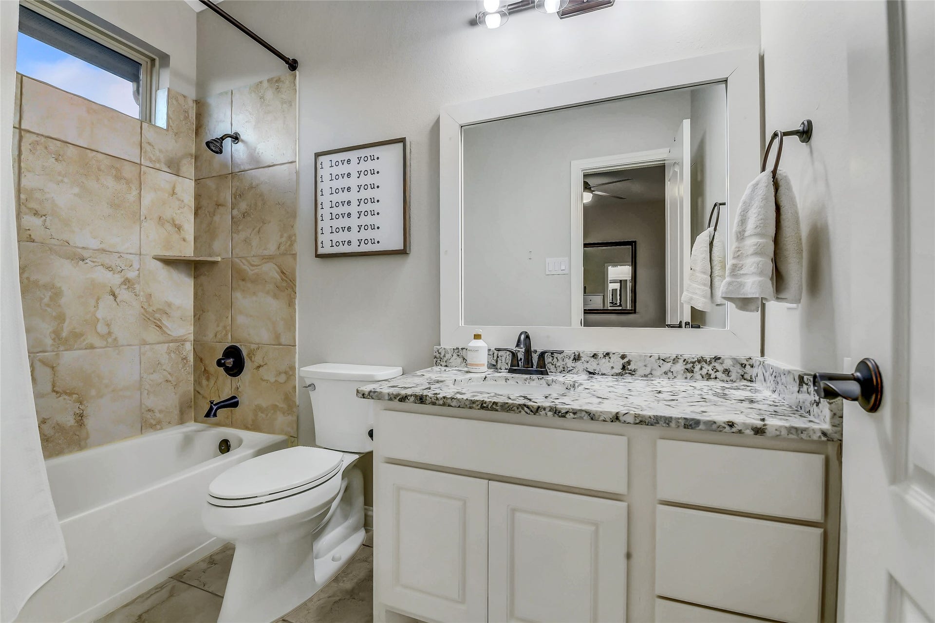 5410 Briarcliff Lane, Fulshear, TX 77441 Private ensuite bathroom features a granite vanity, tiled tub/shower combination with a window for natural light, and stylish finishes.