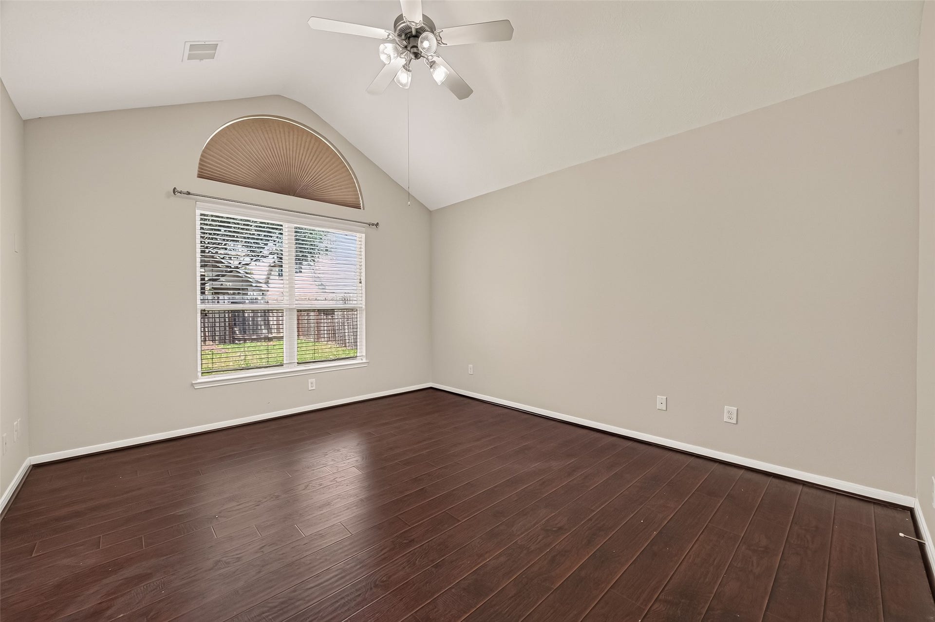 3635 Cottage Manor Lane, Katy, TX 77494 Primary bedroom with a vaulted ceiling, ceiling fan, arched window with a fan shade, and views of the backyard.