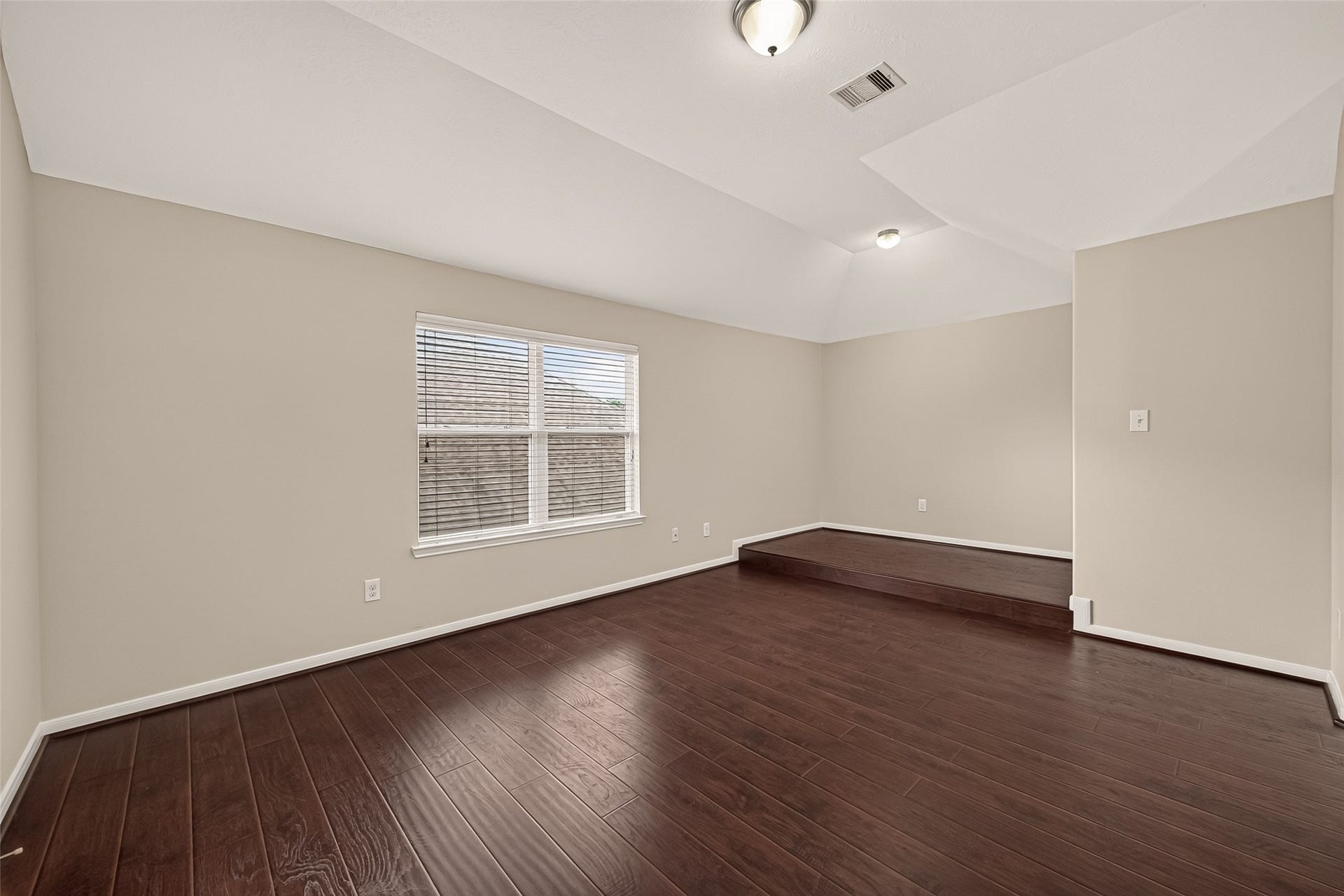 3635 Cottage Manor Lane, Katy, TX 77494 Spacious upstairs game room with a vaulted ceiling, large window, and a raised step-up area for a bar, lounge, or play space.
