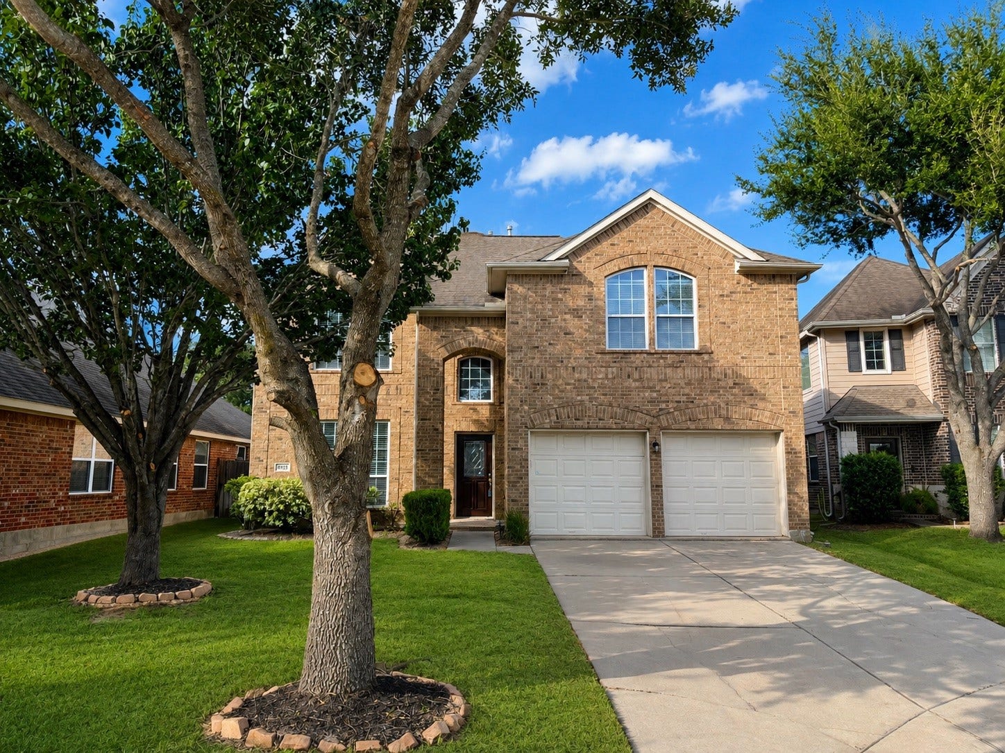 3635 Cottage Manor Lane, Katy, TX 77494 Two-story brick home with arched windows, an attached two-car garage, mature shade trees, and a well-kept lawn.