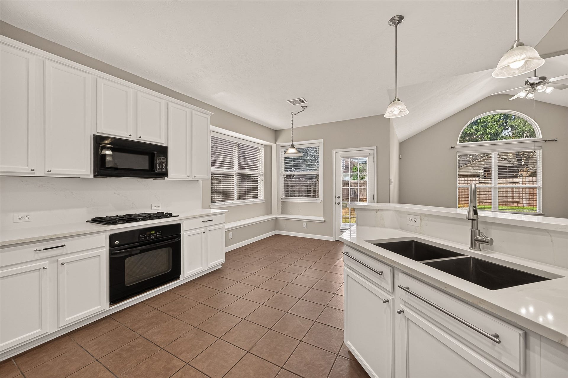 3635 Cottage Manor Lane, Katy, TX 77494 This kitchen view showcases a double-basin sink, high-arc faucet, veined countertops, and a gas cooktop with built-in oven. The breakfast nook and adjoining living room provide backyard views and an open layout for everyday living.