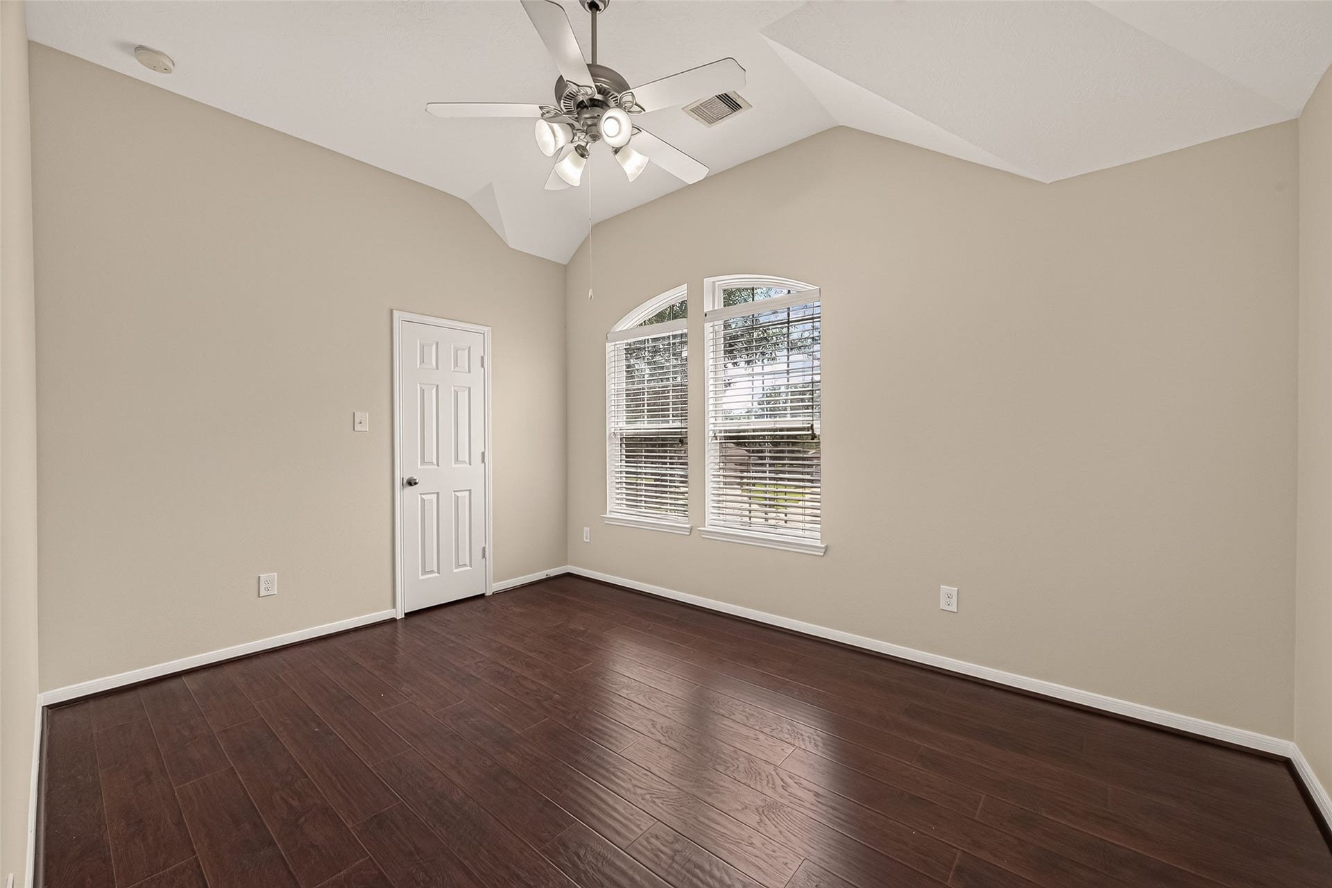 3635 Cottage Manor Lane, Katy, TX 77494 Vaulted ceiling, a pair of arched-top windows, and a ceiling fan make this bedroom feel open and airy.