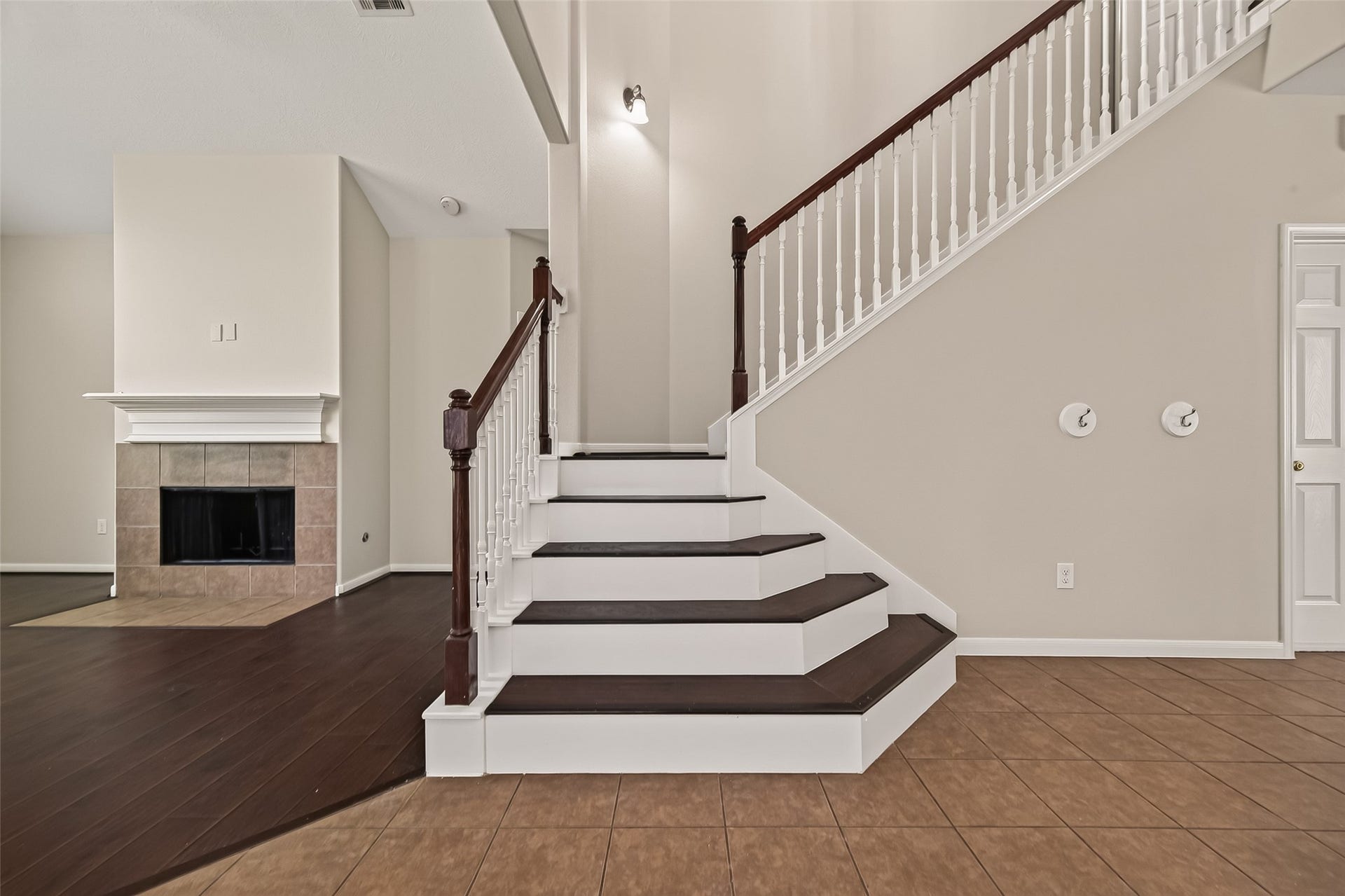 3635 Cottage Manor Lane, Katy, TX 77494 Two-tone staircase with dark treads, white risers, and a stained handrail, positioned between the living room and the entry.
