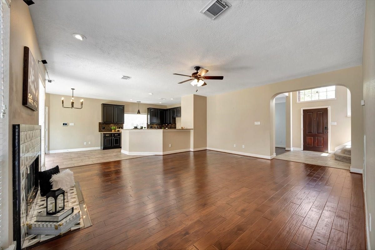 Bright formal living space with warm engineered wood flooring and natural light.