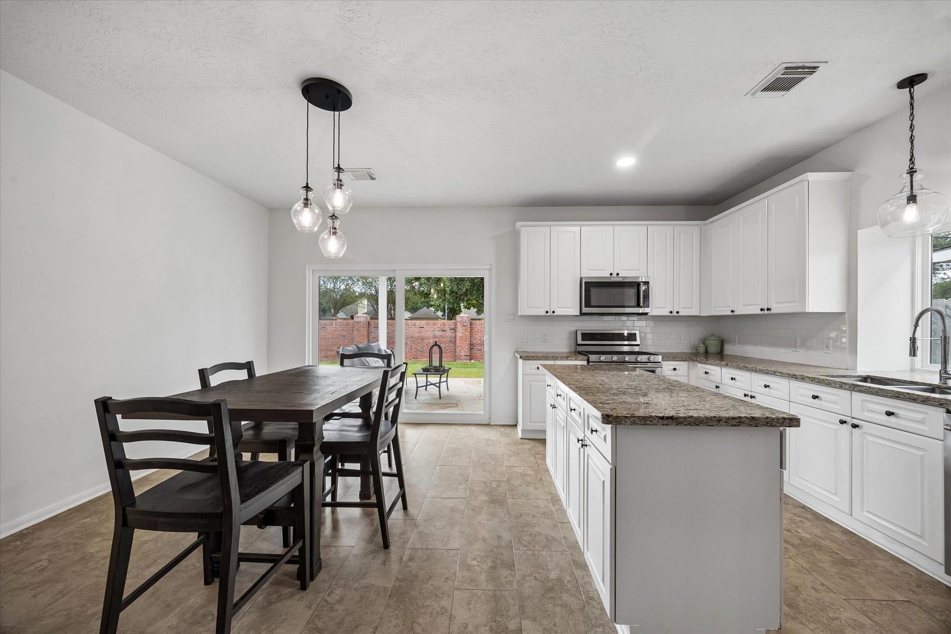Open kitchen and dining area with granite countertops, generous workspace and easy access to the backyard.
