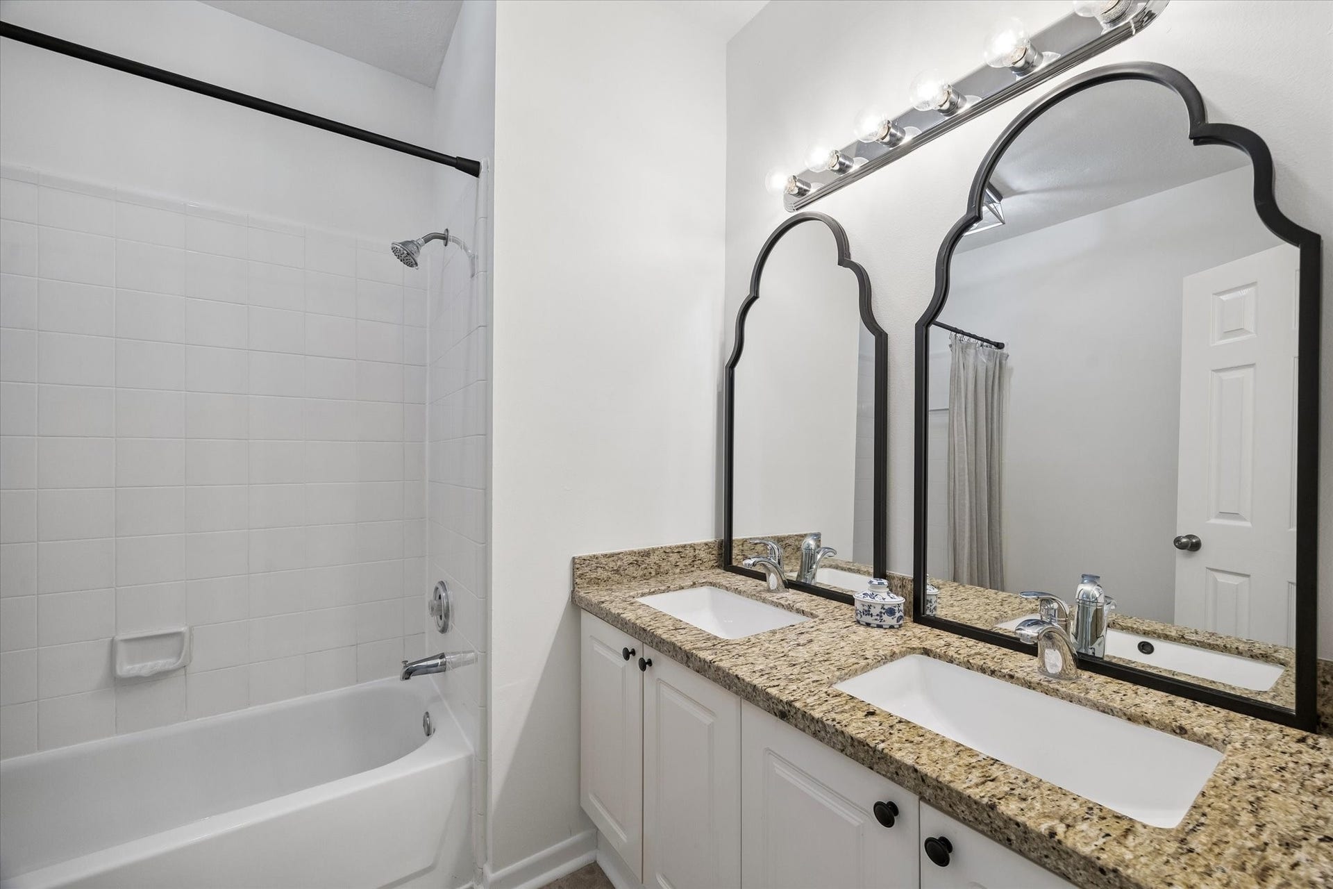 Secondary bath with tub/shower combination and a spacious vanity with dual sinks.