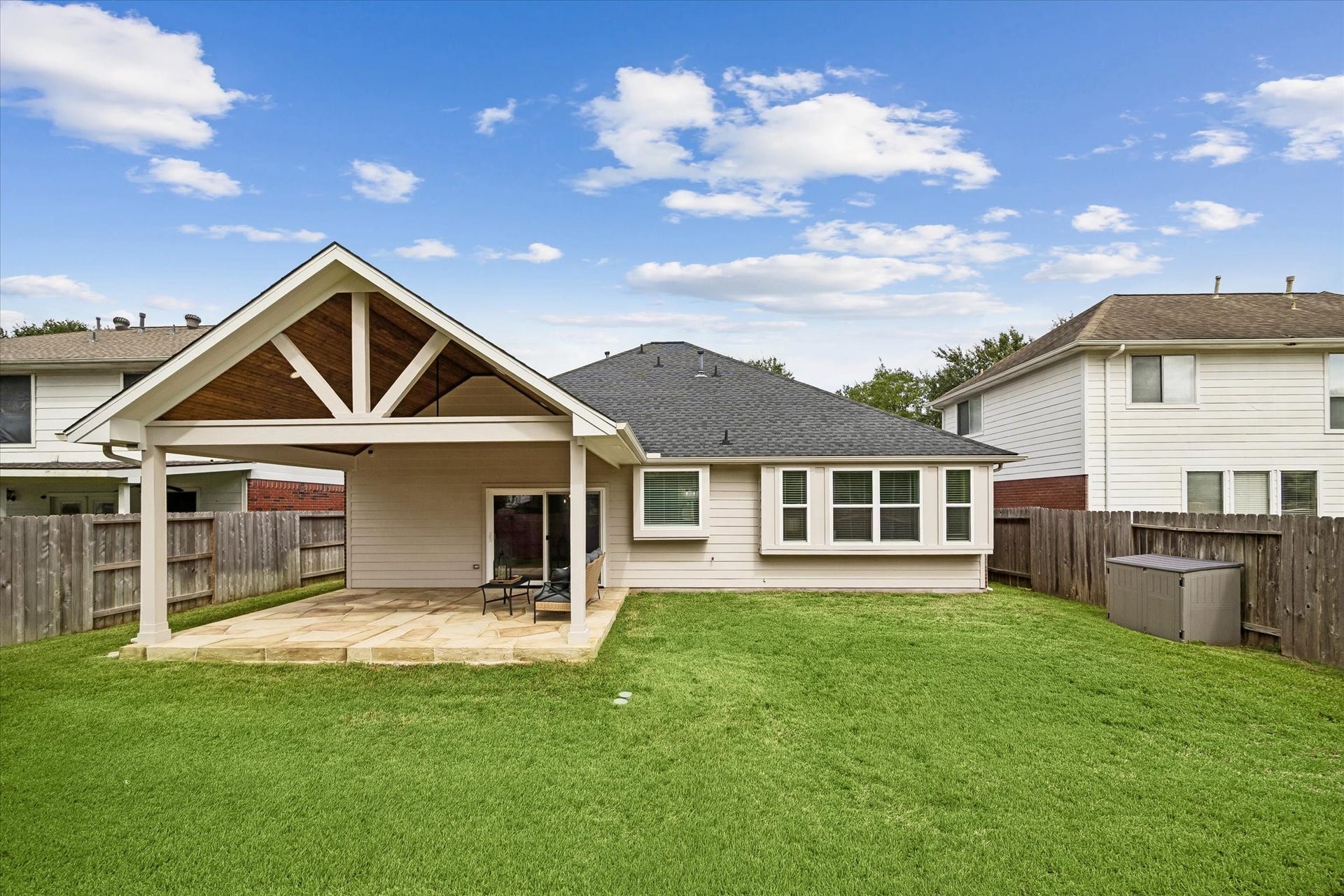A wide backyard view highlights the scale of the new covered patio and the home's outdoor living potential.