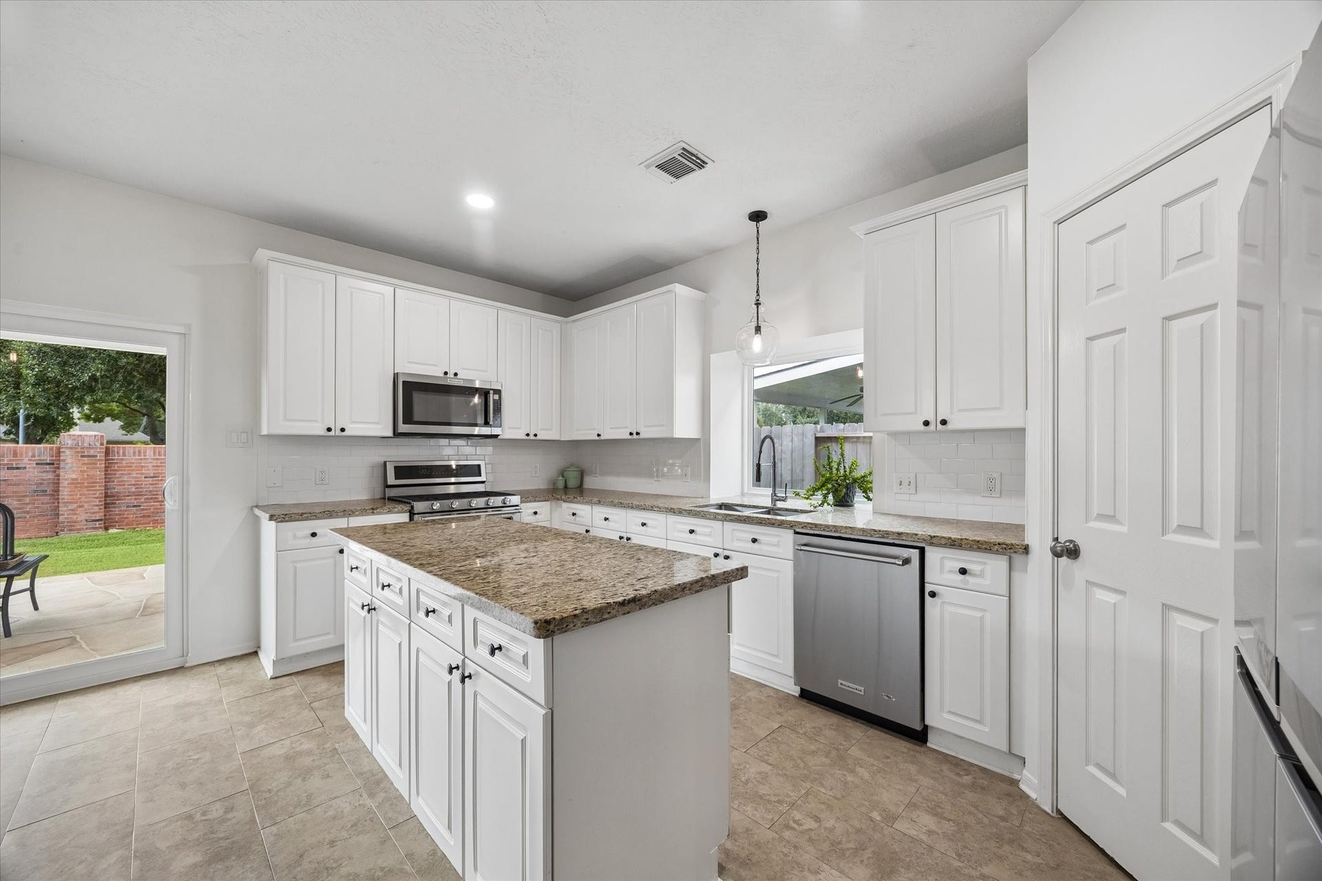 The kitchen features granite countertops, abundant cabinetry, stainless steel appliances and a large island with additional storage.