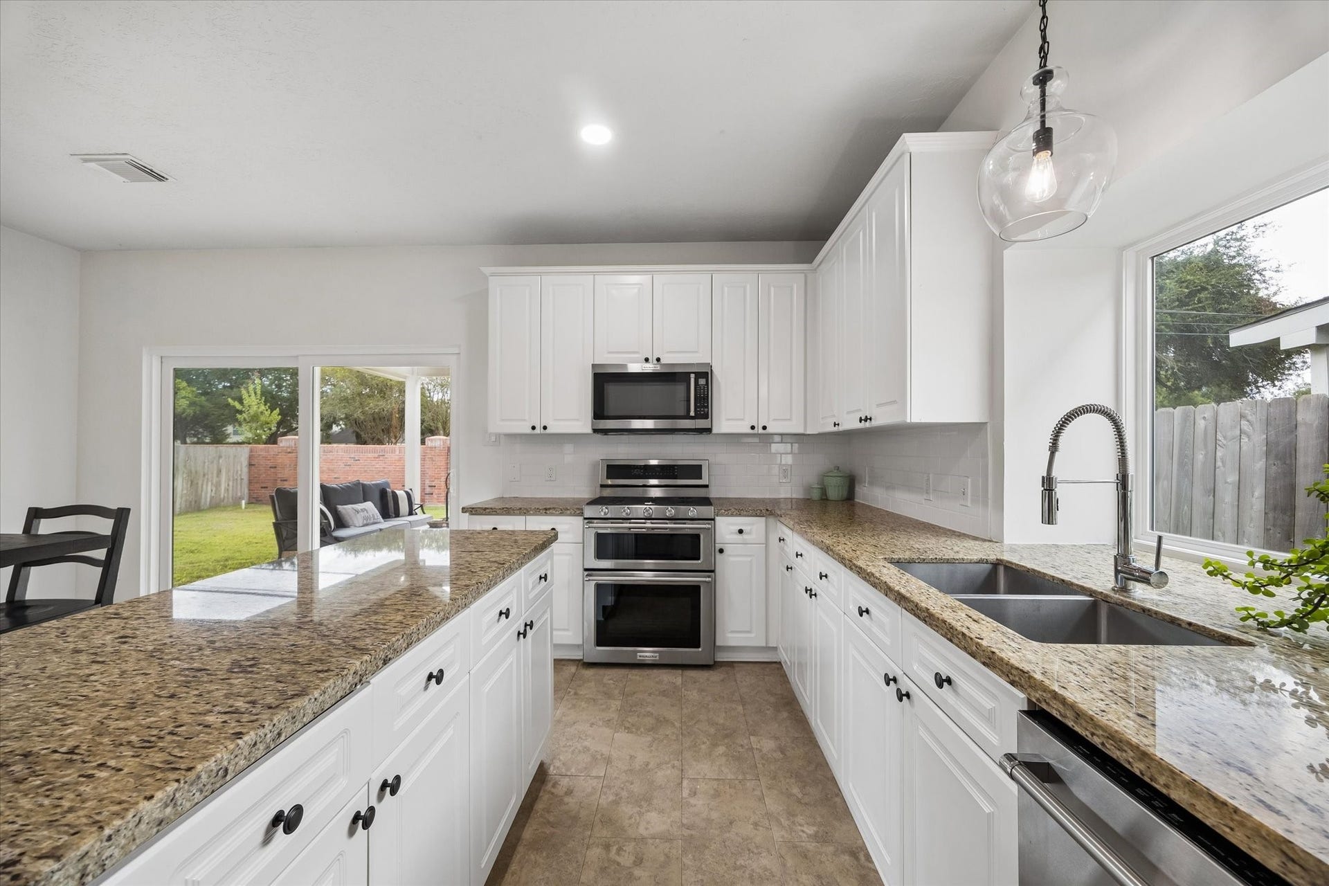 Generous kitchen workspace with granite countertops, abundant cabinetry and stainless steel appliances.