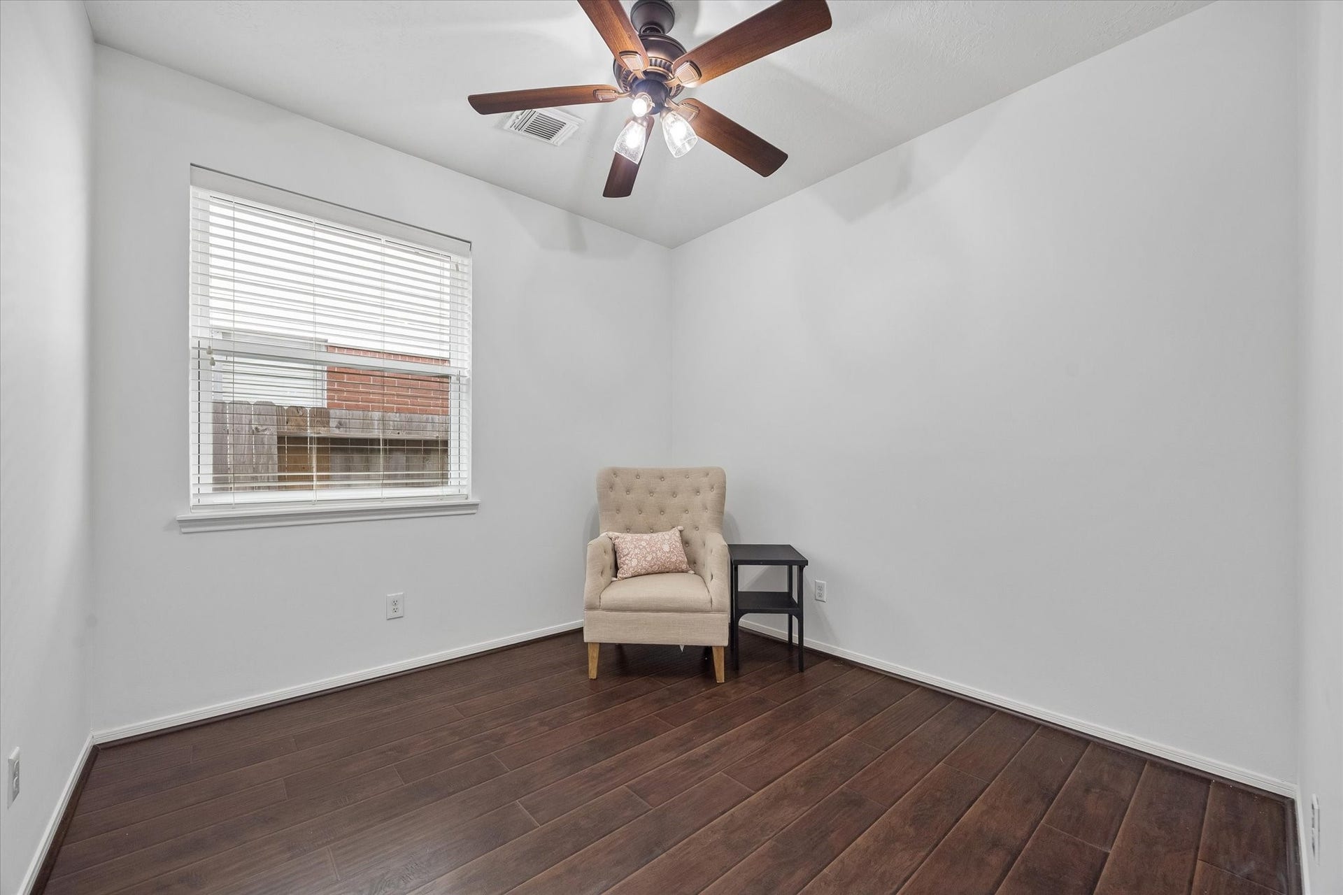 Secondary bedroom with wood-look flooring, ceiling fan and natural light.