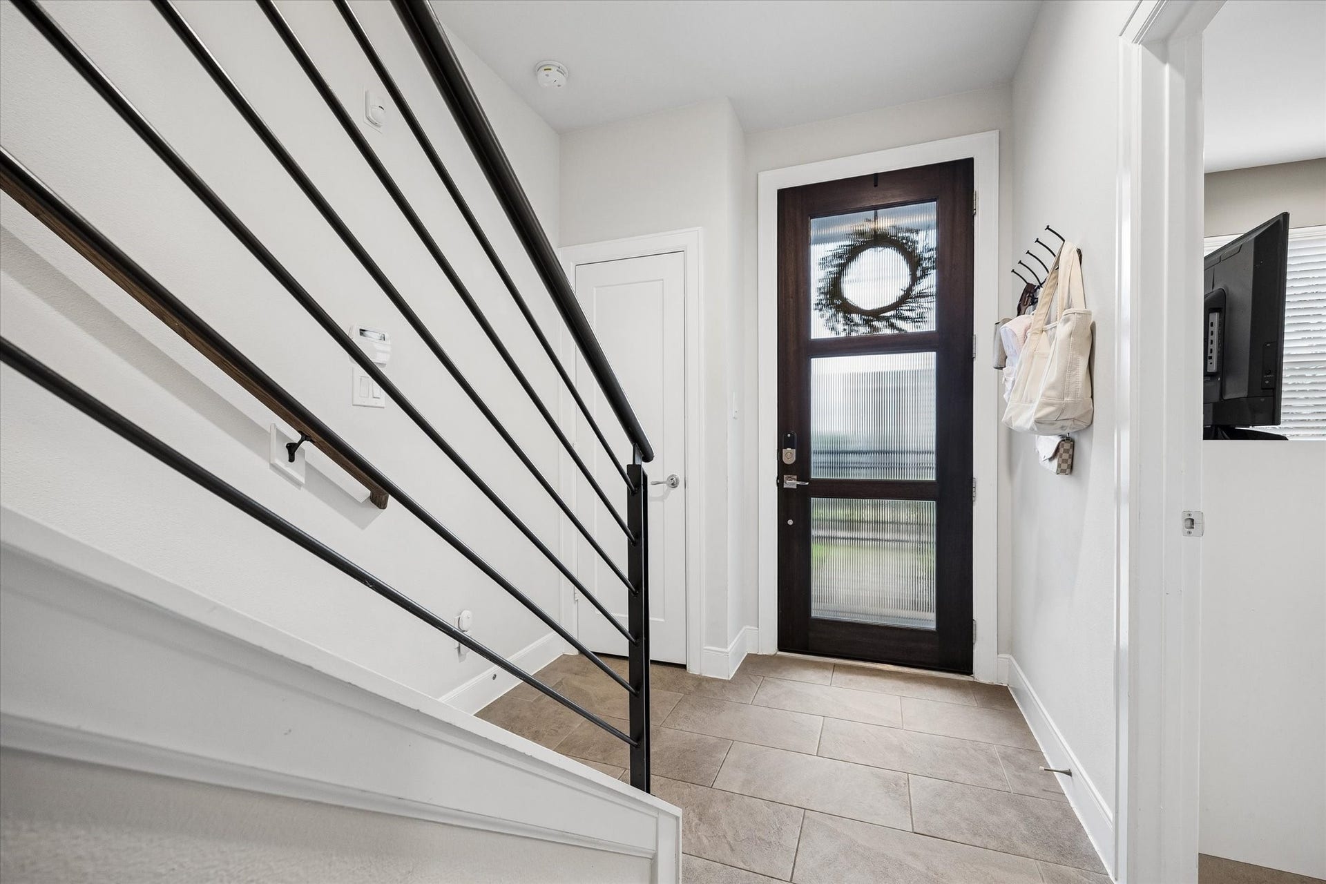 2491 W 11th Street, Houston, TX 77008 Bright entryway features a modern glass-paneled front door and sleek metal stair railing. Neutral finishes and tile flooring create a clean, contemporary first impression.