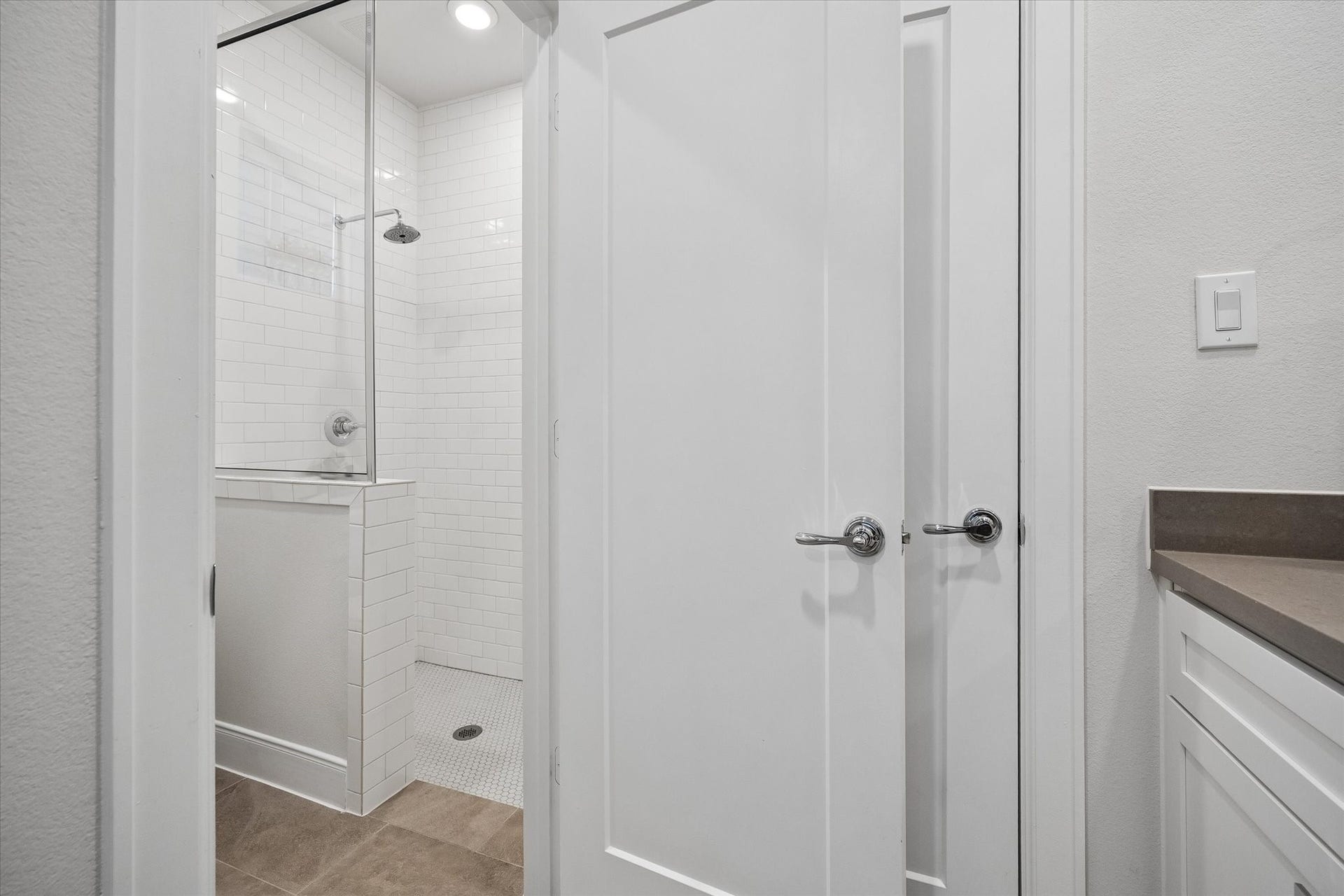 2491 W 11th Street, Houston, TX 77008 Full bath features a walk-in shower surrounded by classic white subway tile. A glass enclosure and neutral tile flooring give the space a clean, streamlined look.