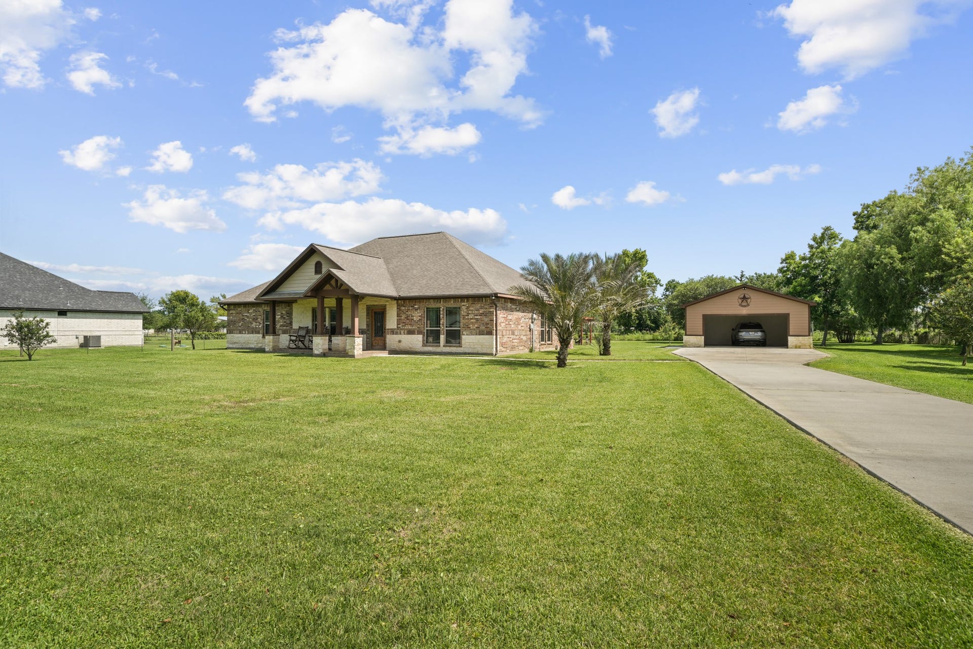 11021 32nd Street, Santa Fe, TX 77510 Experience serene country living with a charming front porch featuring inviting rocking chairs and elegant stone column details.