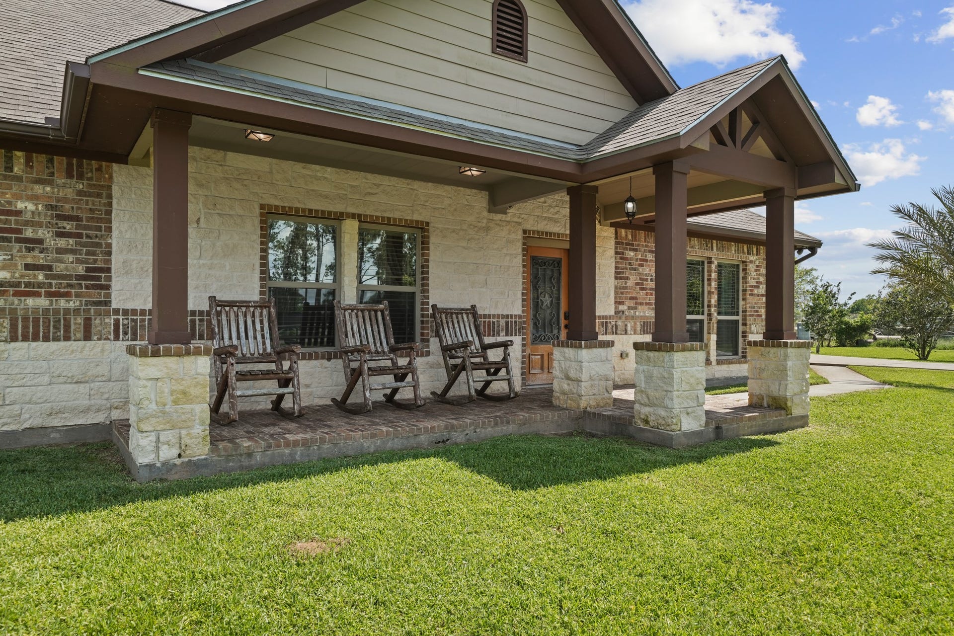 11021 32nd Street, Santa Fe, TX 77510 Relax in style on this charming front porch, featuring inviting rocking chairs and elegant stone column details.