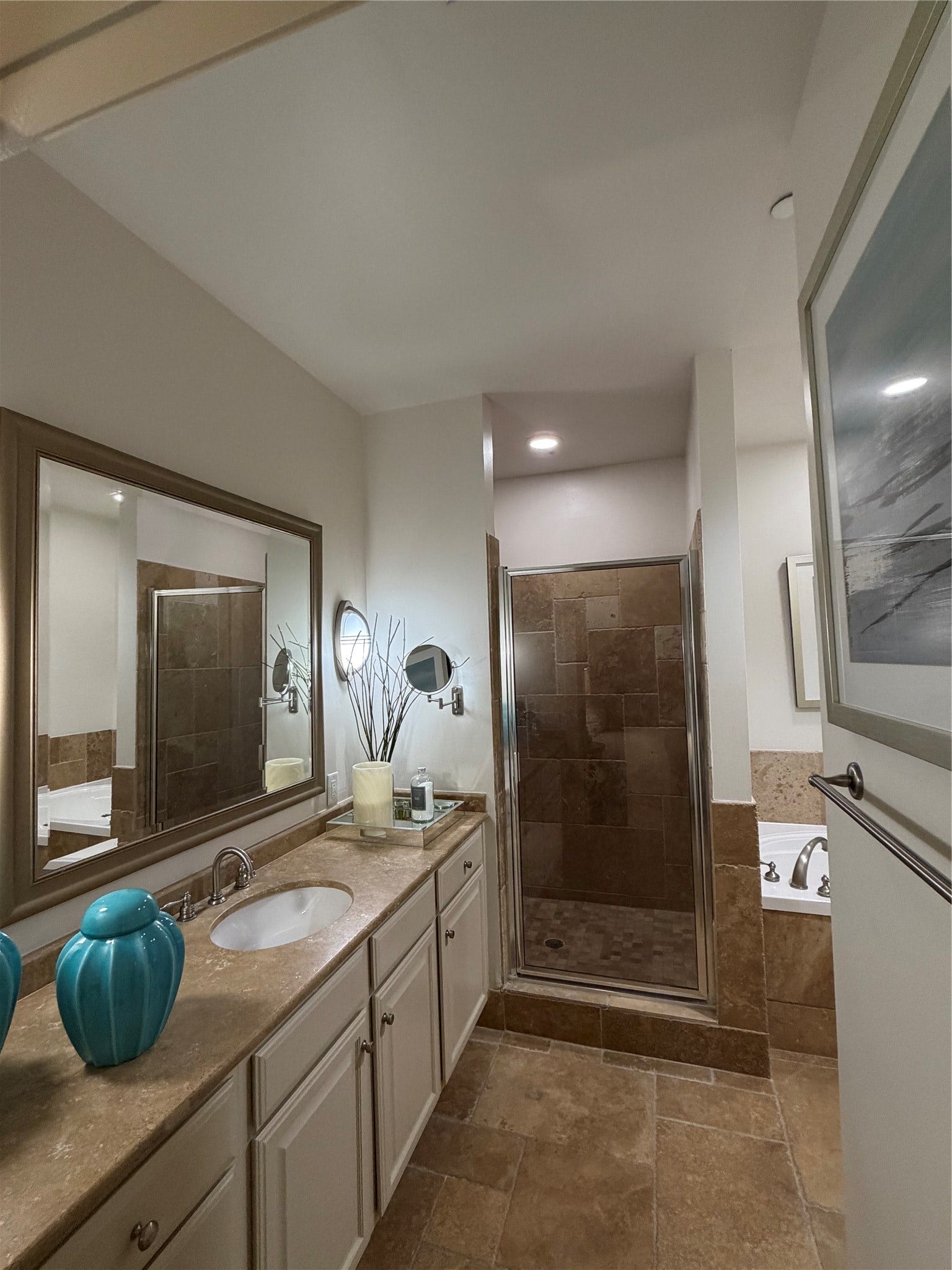 Note the extra storage in the vanity area, oversized framed mirror and frameless walk-in shower. Separate deep soaking tub.