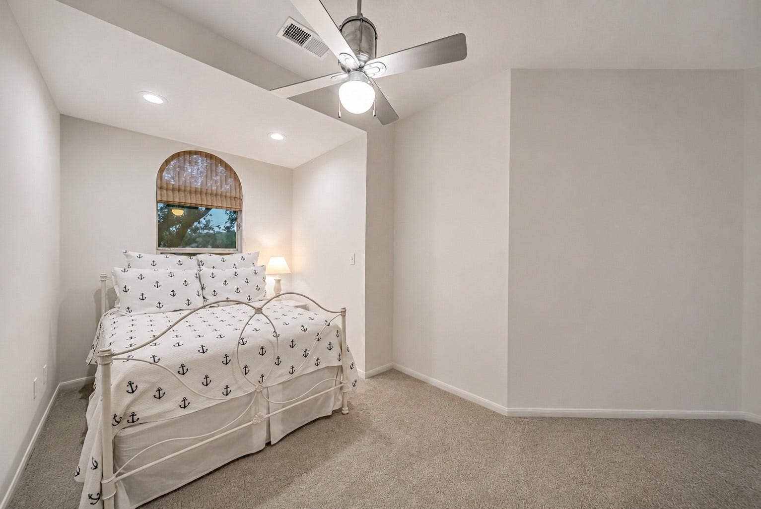 318 Bayshore Drive, Montgomery, TX 77356 Bedroom 2 features new carpet, a tray ceiling with recessed lighting, and a charming arched window that brings in abundant natural light.