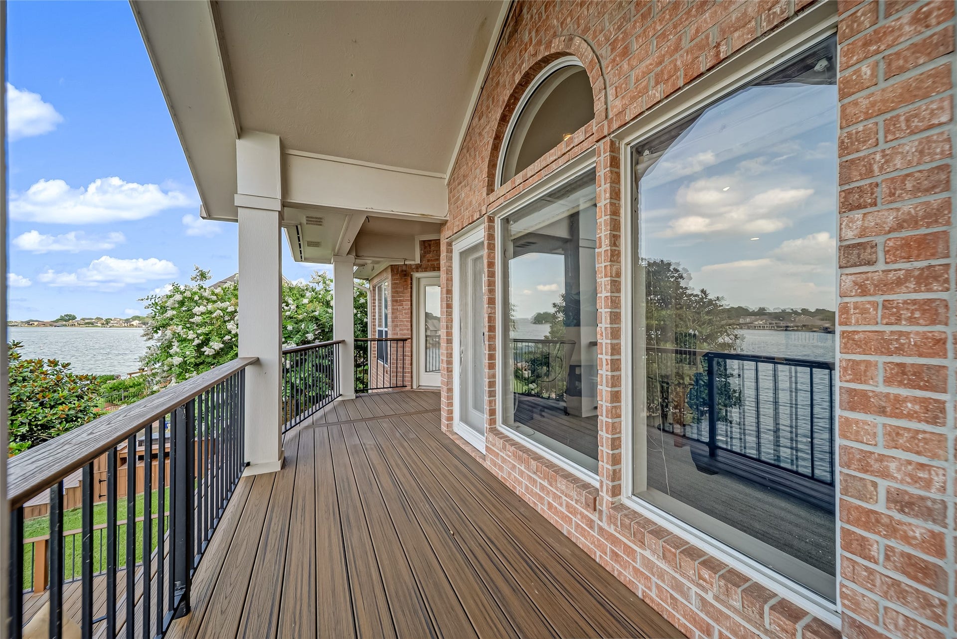 318 Bayshore Drive, Montgomery, TX 77356 Framed by elegant architectural details, the wraparound balcony showcases stunning lake views while providing a seamless extension of the home's luxury living spaces, perfect for year-round outdoor enjoyment.