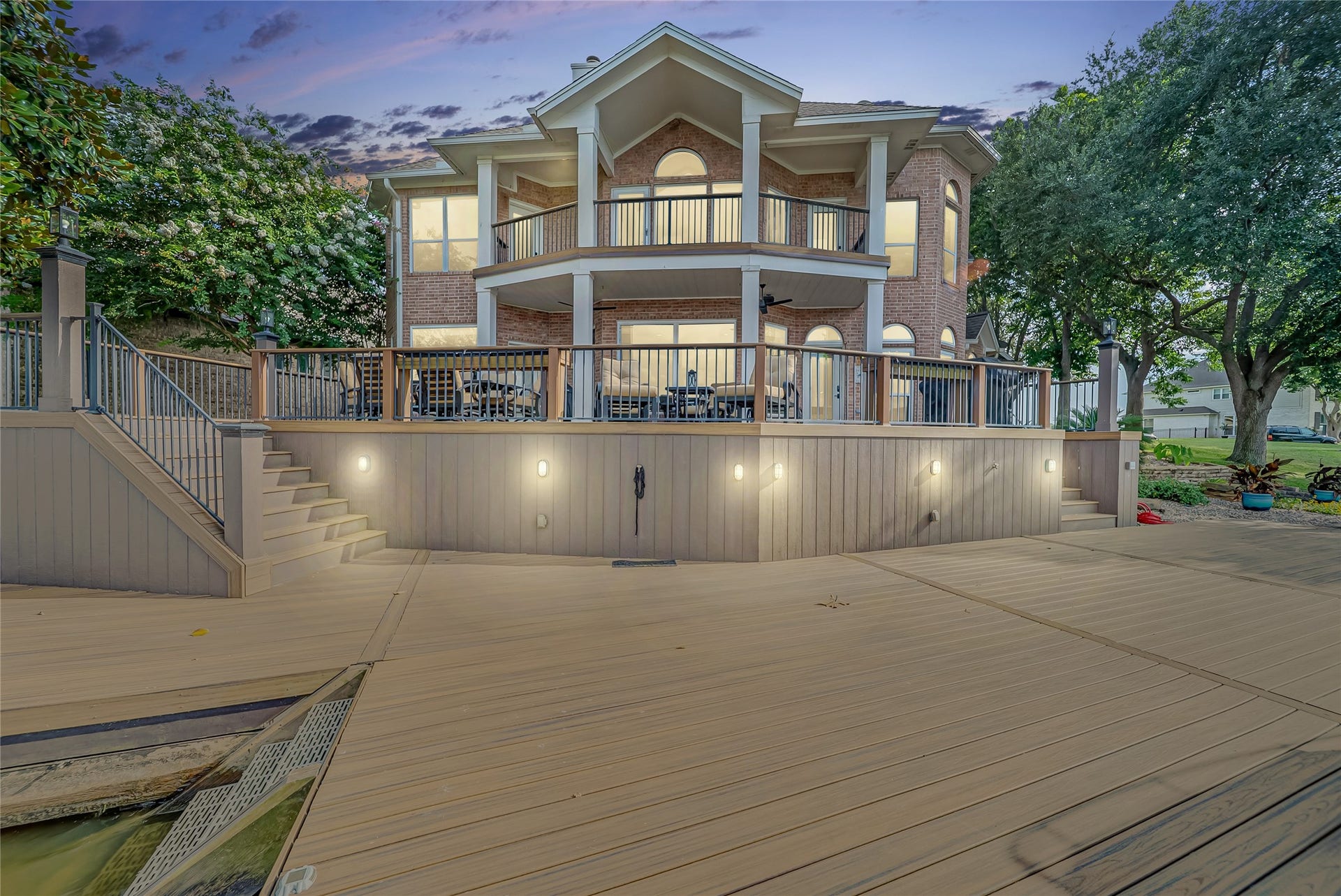 318 Bayshore Drive, Montgomery, TX 77356 As the sun sets, the home's illuminated exterior creates a breathtaking lakeside presence, reflecting beautifully across the water and offering an unforgettable evening backdrop.