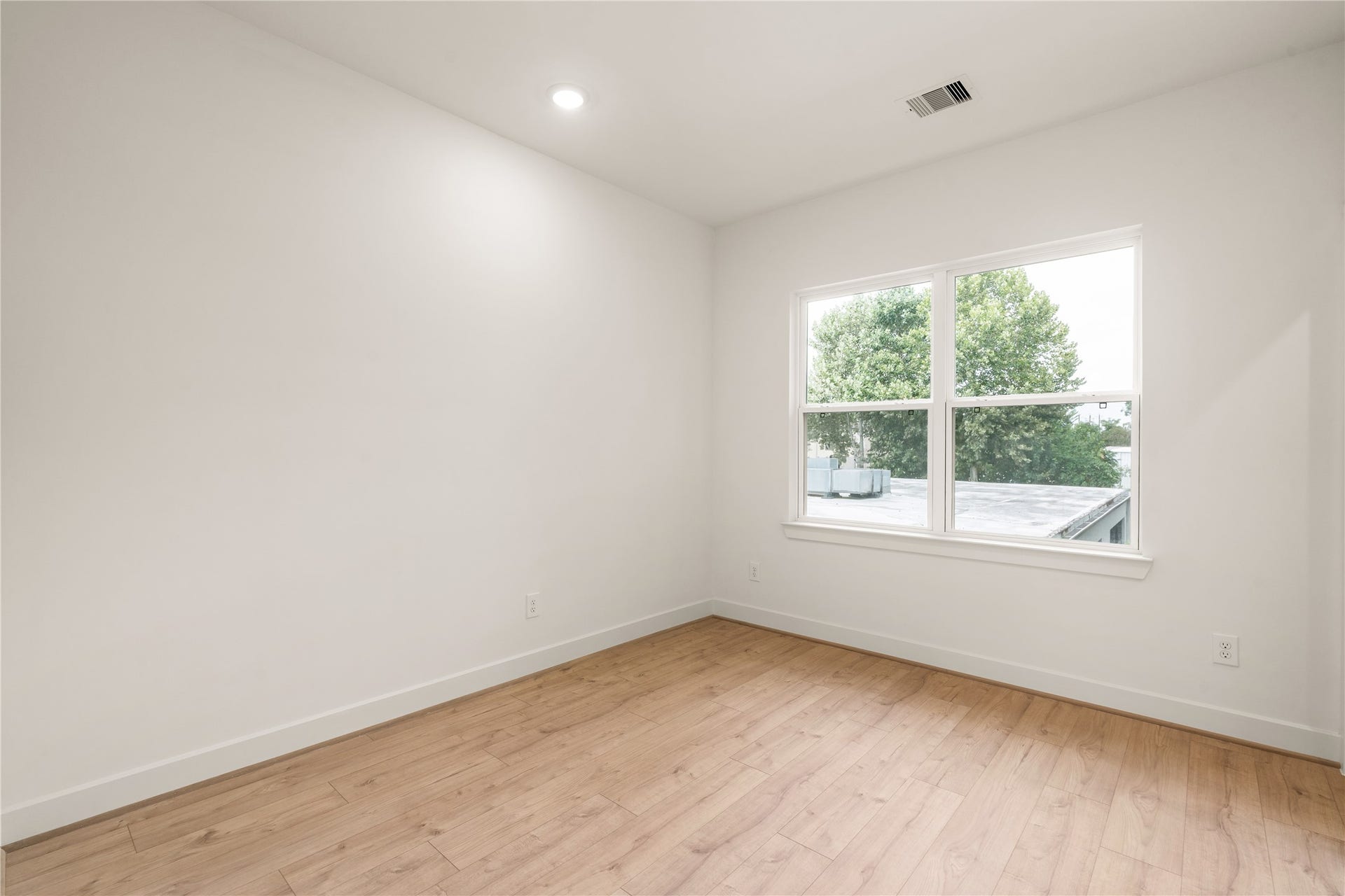 5016 Schuler Street, Houston, TX 77007 Secondary bedroom light-filled layout with large picture window, wide-plank wood-look flooring, and crisp modern trim.