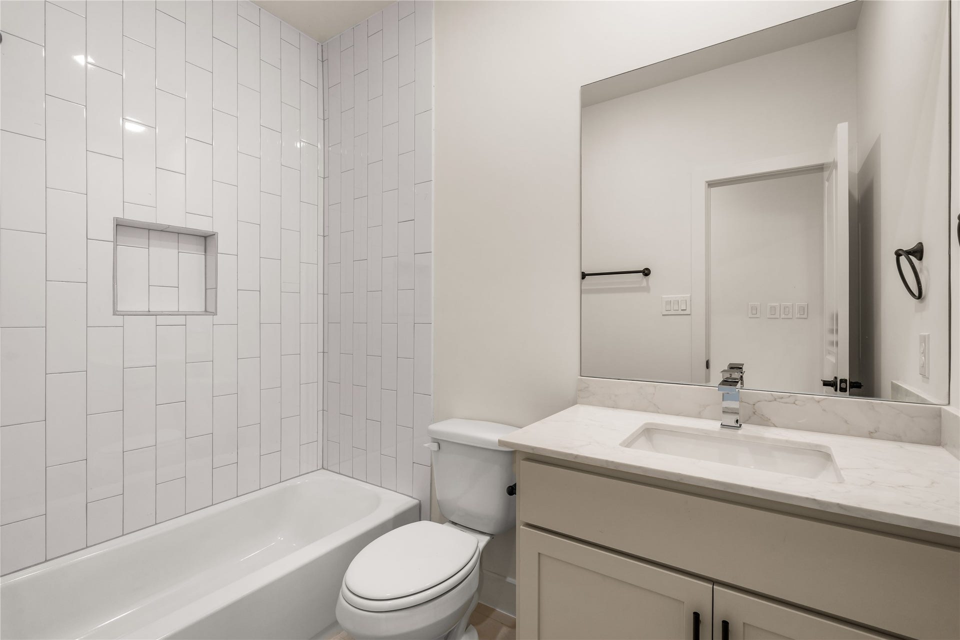 5016 Schuler Street, Houston, TX 77007 Secondary bath designer white vertical stack tile surround, inset storage niche, deep soaking tub, and quartz-topped vanity.
