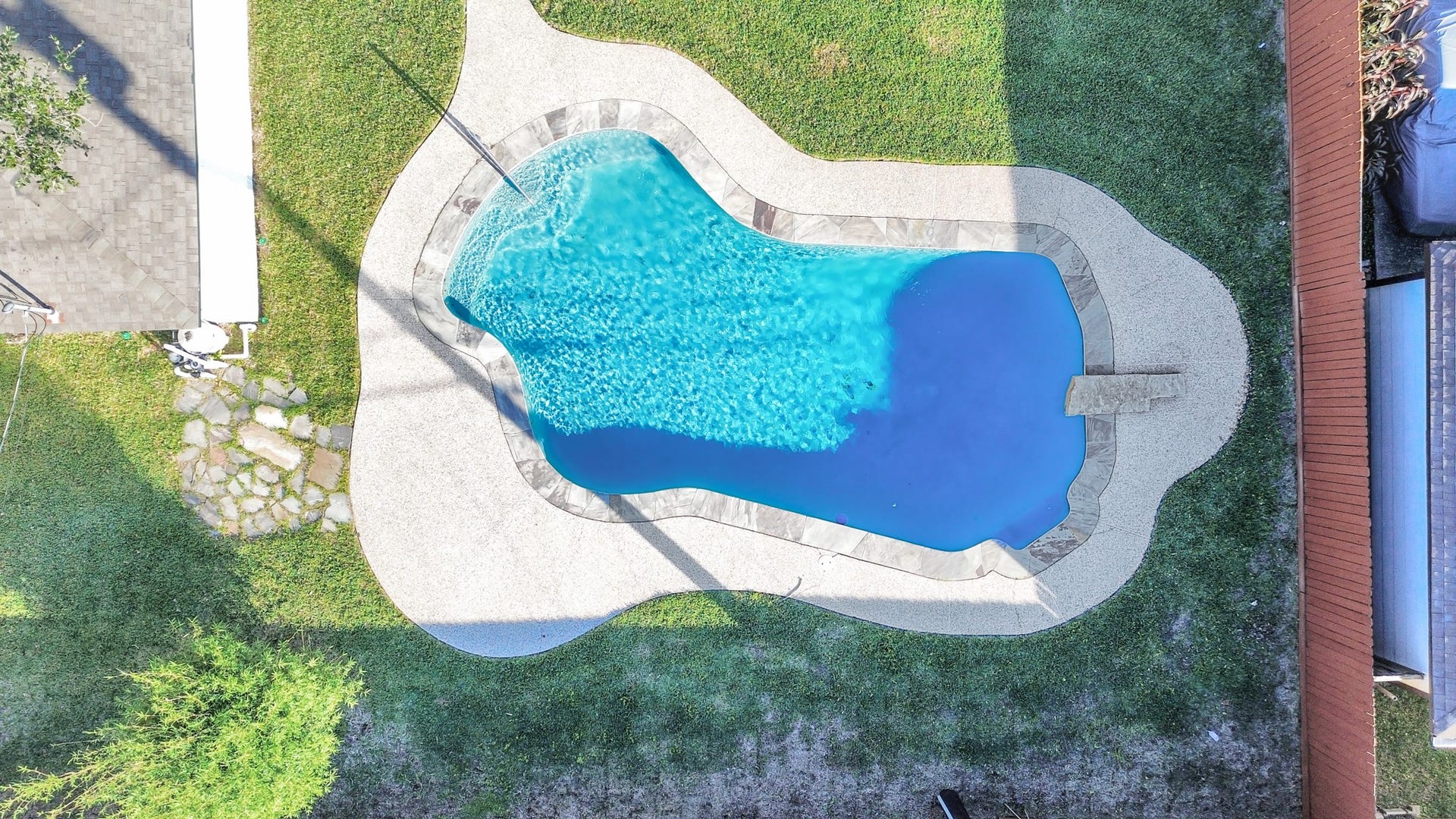 6035 Cartagena Street, Houston, TX 77035 An aerial view showcases the magnificent pool, surrounded by elegant stone coping and featuring a unique stone diving board, creating a striking focal point in the backyard. Just in time for summertime!