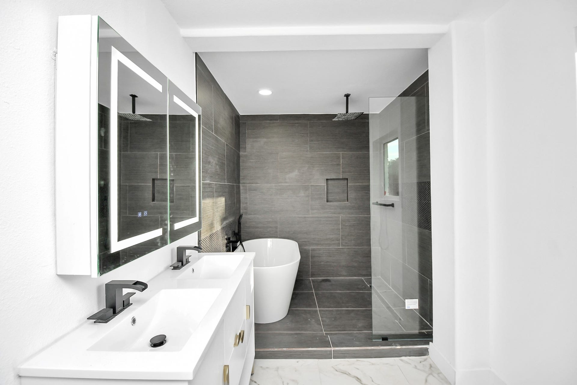 6035 Cartagena Street, Houston, TX 77035 The downstairs bathroom offers every luxury, featuring touch screen smart mirrors, a seamless glass shower, and a freestanding soaking tub, leaving nothing to be desired.
