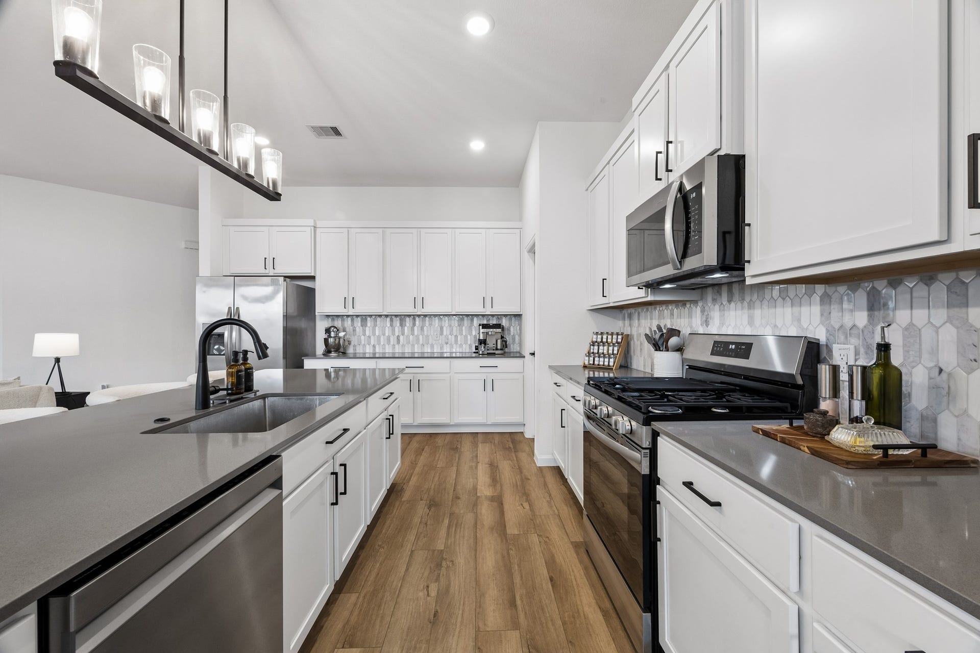 2118 Cottage Bridge Road, League City, TX 77573 The kitchen color palette is elegant and classic. The new dishwasher intergrates seamlessly with the stainless steel appliances, charcoal quartz countertops and backsplash. The upgrades feature a light fixture over the island sink, and hardware on the cabinets.