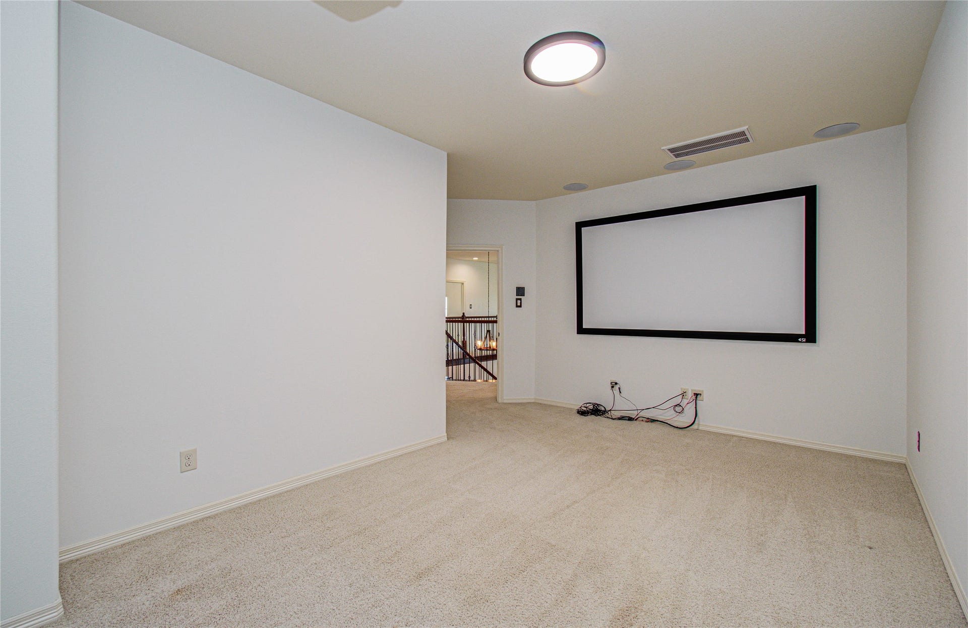Experience cinematic entertainment at home in this spacious media room, featuring a built-in screen and ample space for seating.
