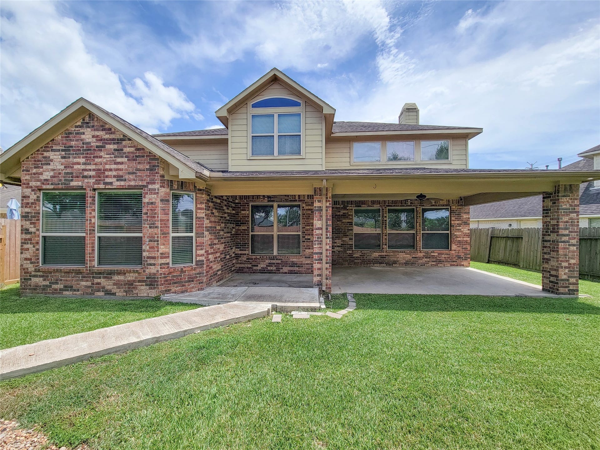 2210 Pearl Bay Court, Pearland, TX 77584 Charming two-story home with a brick exterior, spacious covered patio, and a well-maintained lawn, perfect for outdoor entertaining.