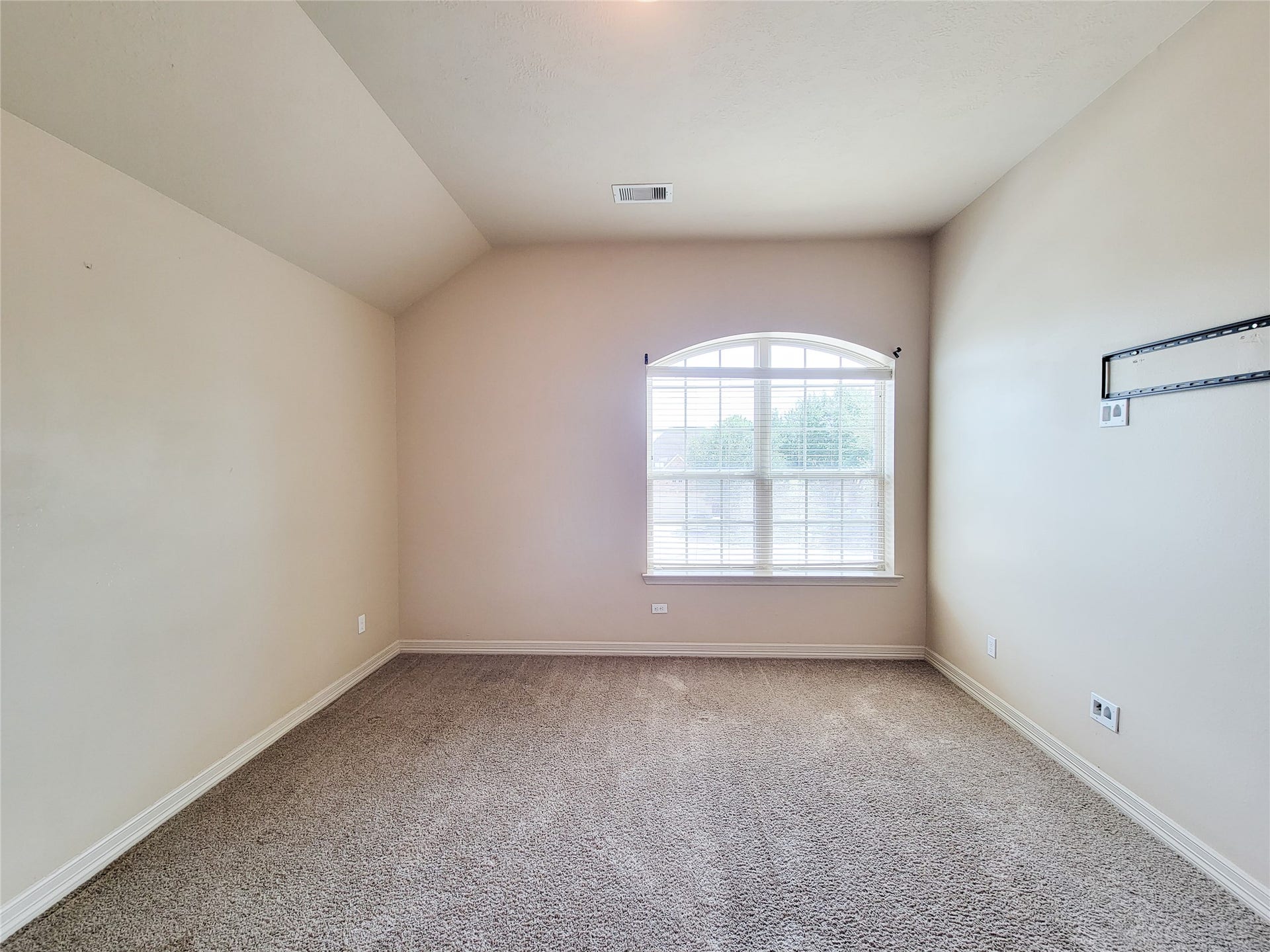 2210 Pearl Bay Court, Pearland, TX 77584 This is a bright, unfurnished room with neutral walls and carpeted flooring. It features a large arched window that allows plenty of natural light, and the ceiling is vaulted, adding to the spacious feel.