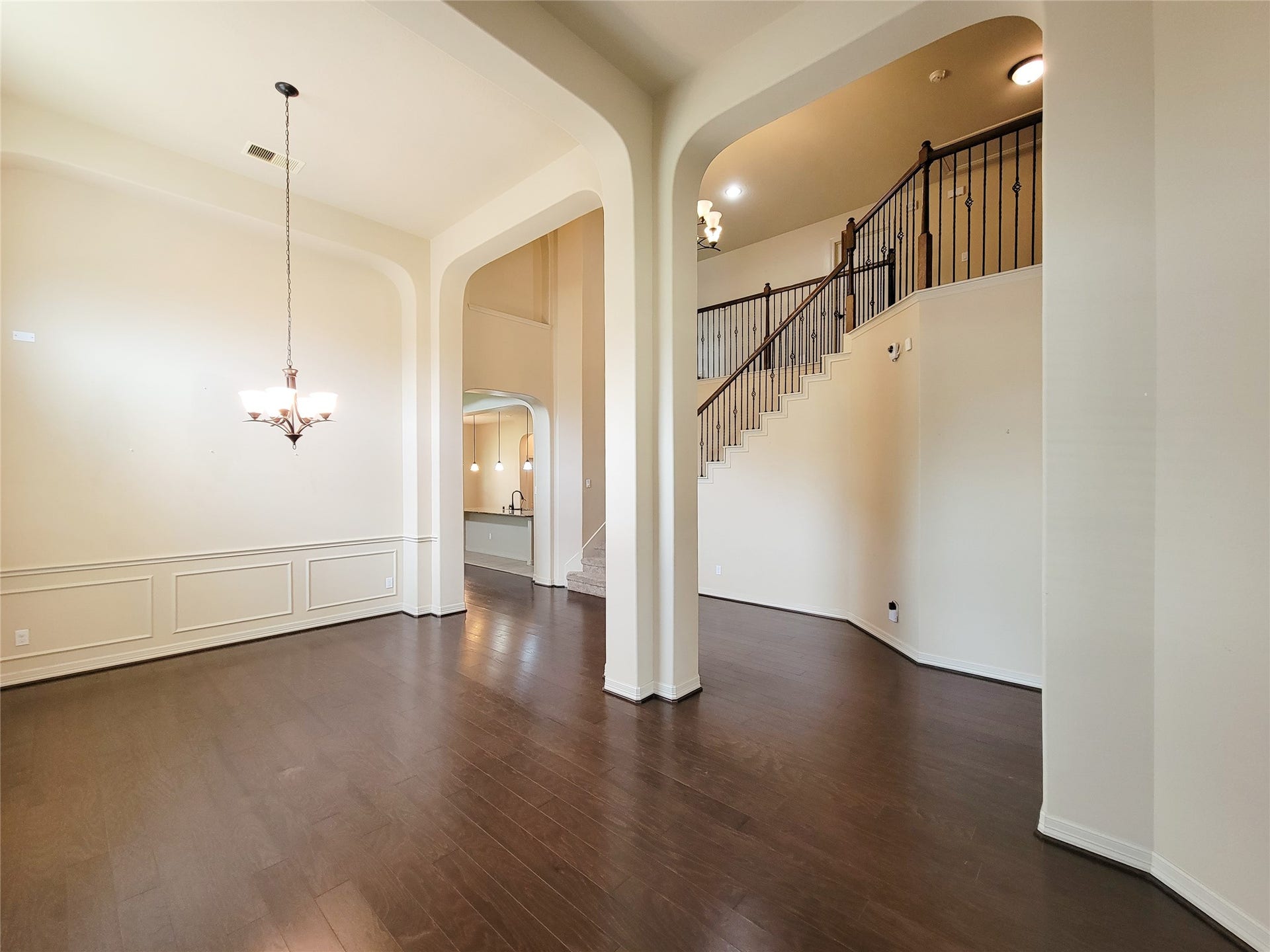2210 Pearl Bay Court, Pearland, TX 77584 This spacious home features high ceilings and an open floor plan with elegant archways. A beautiful staircase leads to the upper level, and large windows fill the space with natural light. The dark wood flooring contrasts nicely with the neutral walls, adding warmth and sophistication.