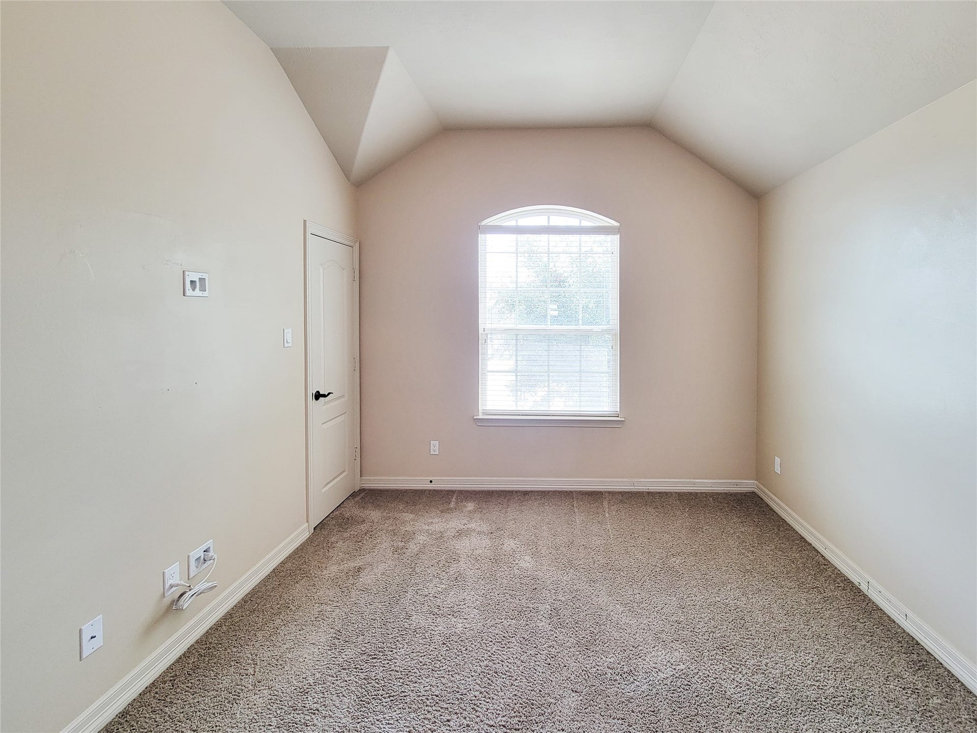 2210 Pearl Bay Court, Pearland, TX 77584 This room features a vaulted ceiling and neutral walls with a large window allowing natural light. It has carpeted flooring and a door leading to an adjacent space. Ideal for use as a bedroom or home office.