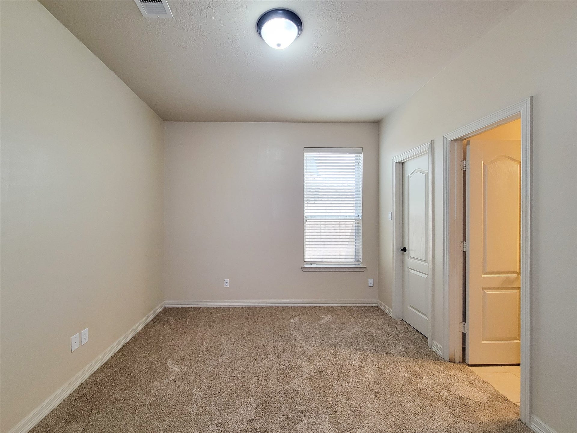 2210 Pearl Bay Court, Pearland, TX 77584 This room features neutral walls, carpeted flooring, a window with blinds for natural light, and two doors, one leading to a connected space. Ideal for a bedroom or home office.