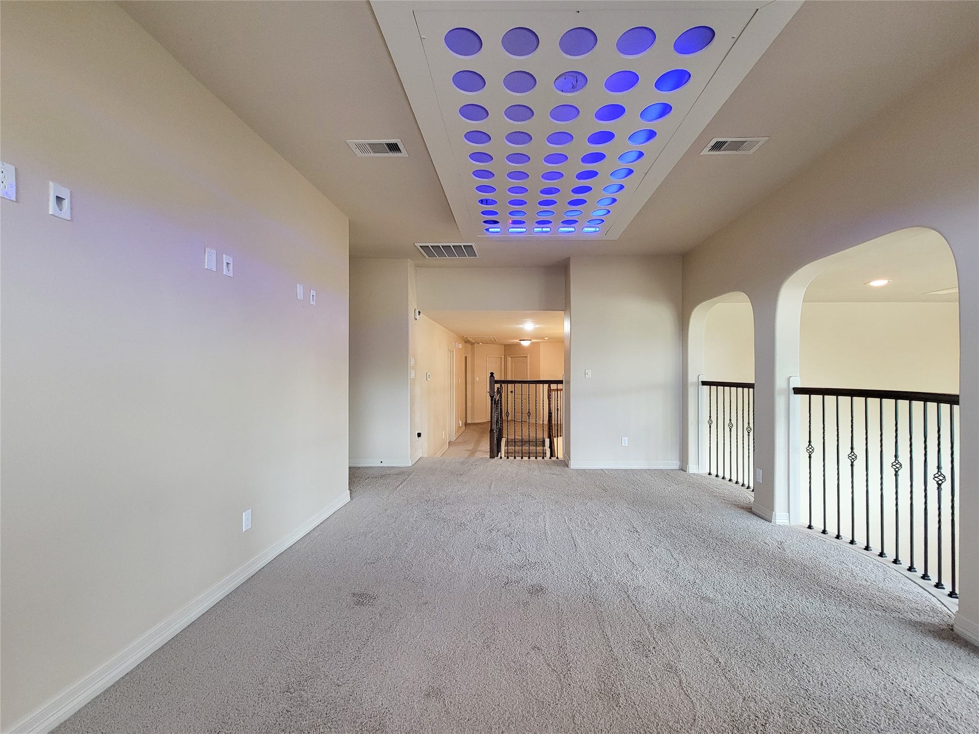 2210 Pearl Bay Court, Pearland, TX 77584 This spacious upstairs area features neutral carpeting, arched openings with stylish railing, and a modern ceiling design with recessed lighting, ideal for a home office or lounge.