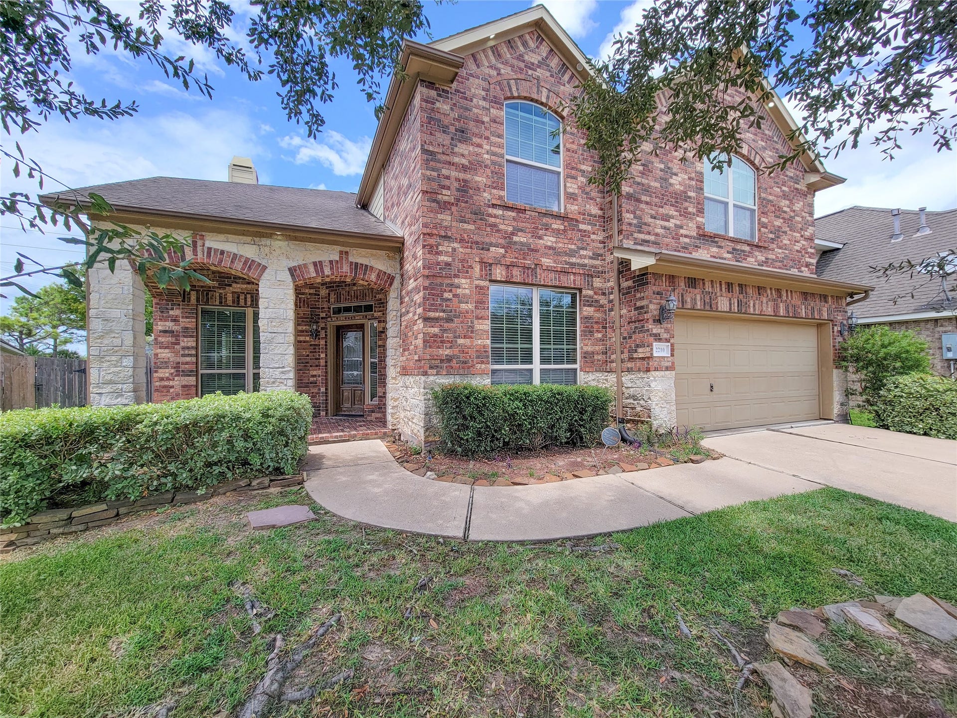 2210 Pearl Bay Court, Pearland, TX 77584 Charming two-story brick and stone home with a manicured front lawn, inviting front porch, and attached two-car garage. Great curb appeal in a desirable neighborhood.