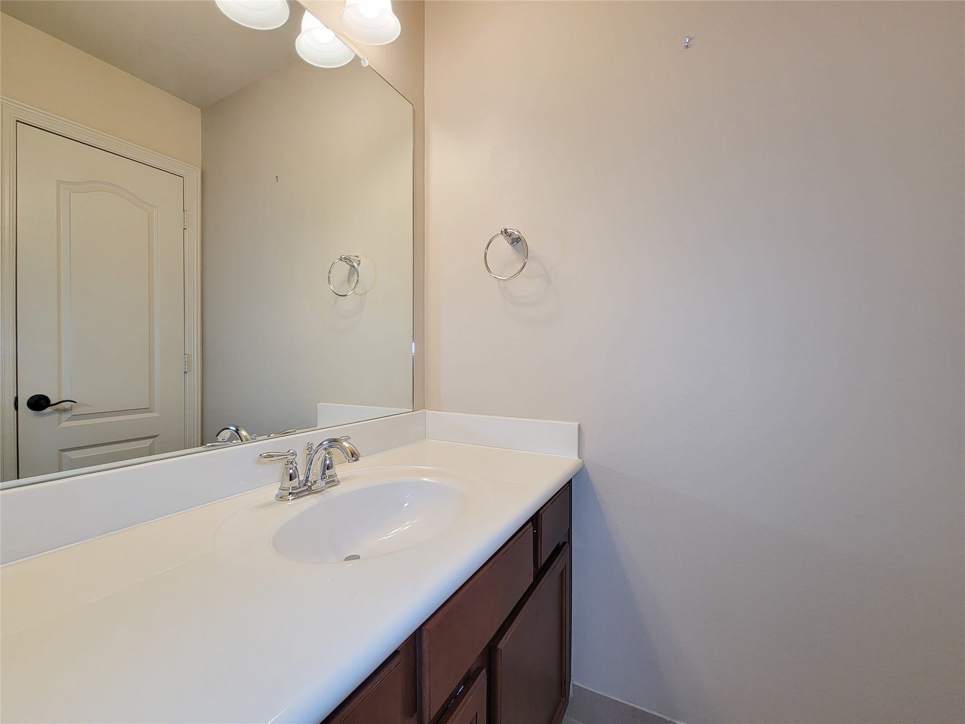 2210 Pearl Bay Court, Pearland, TX 77584 This photo shows a clean, modern bathroom with a large mirror, single sink vanity, and ample countertop space. The neutral wall color and cabinetry provide a simple and elegant look.