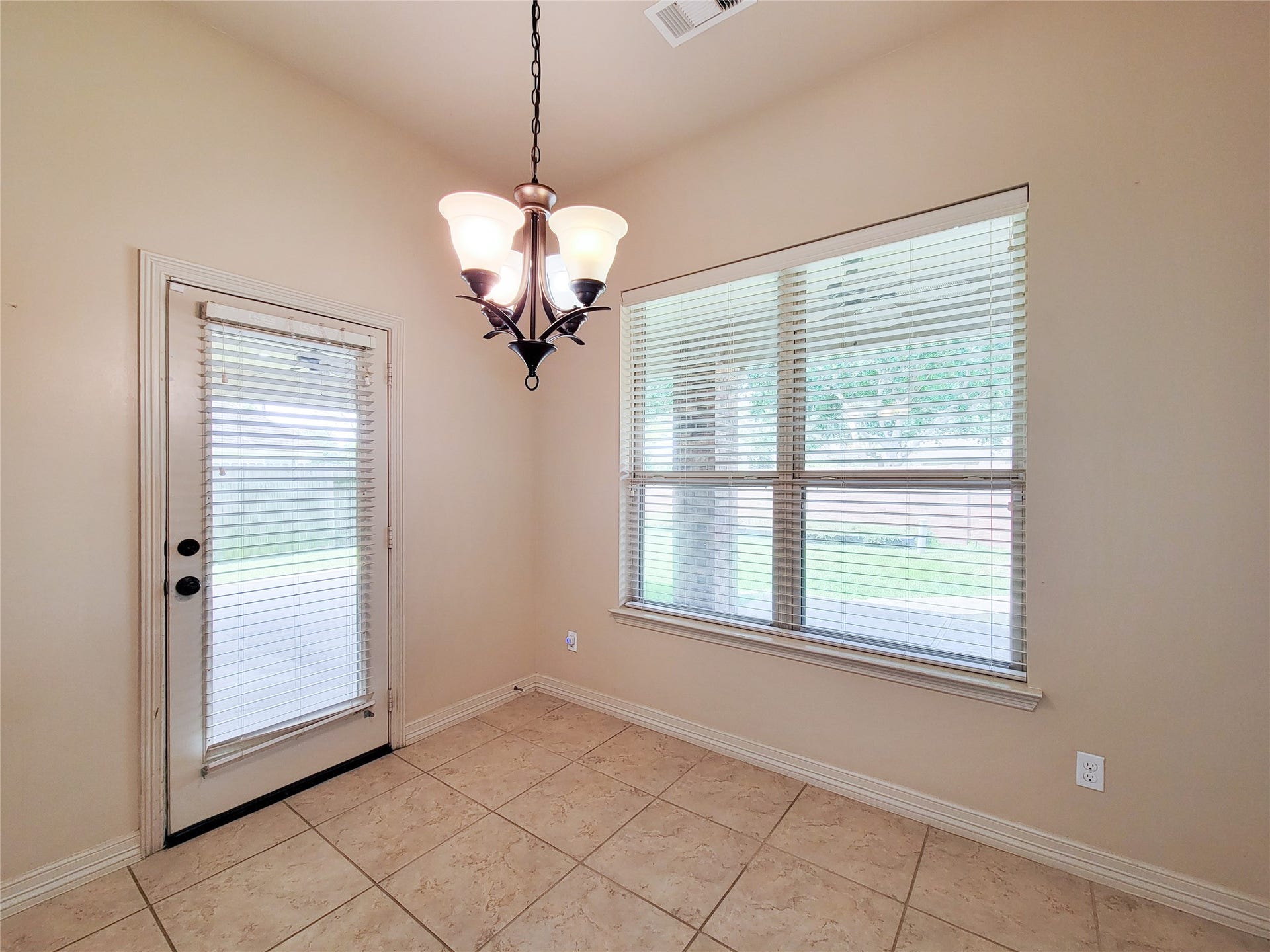 2210 Pearl Bay Court, Pearland, TX 77584 This is a bright dining area with large windows and a glass door leading outside. It features tiled floors, neutral walls, and a stylish overhead light fixture, offering a cozy and inviting space.