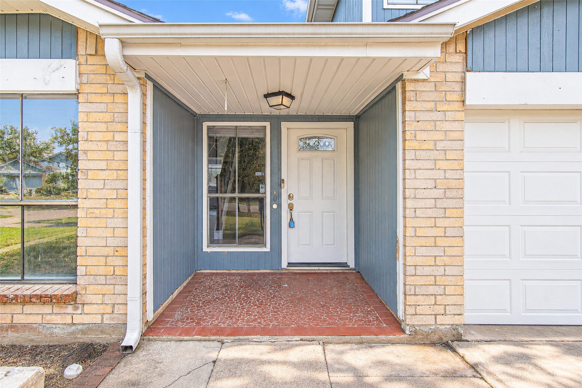 12027 Huntington Park Drive, Houston, TX 77099 Charming entryway featuring a covered porch with a modern white door and brick accents, offering a welcoming first impression.