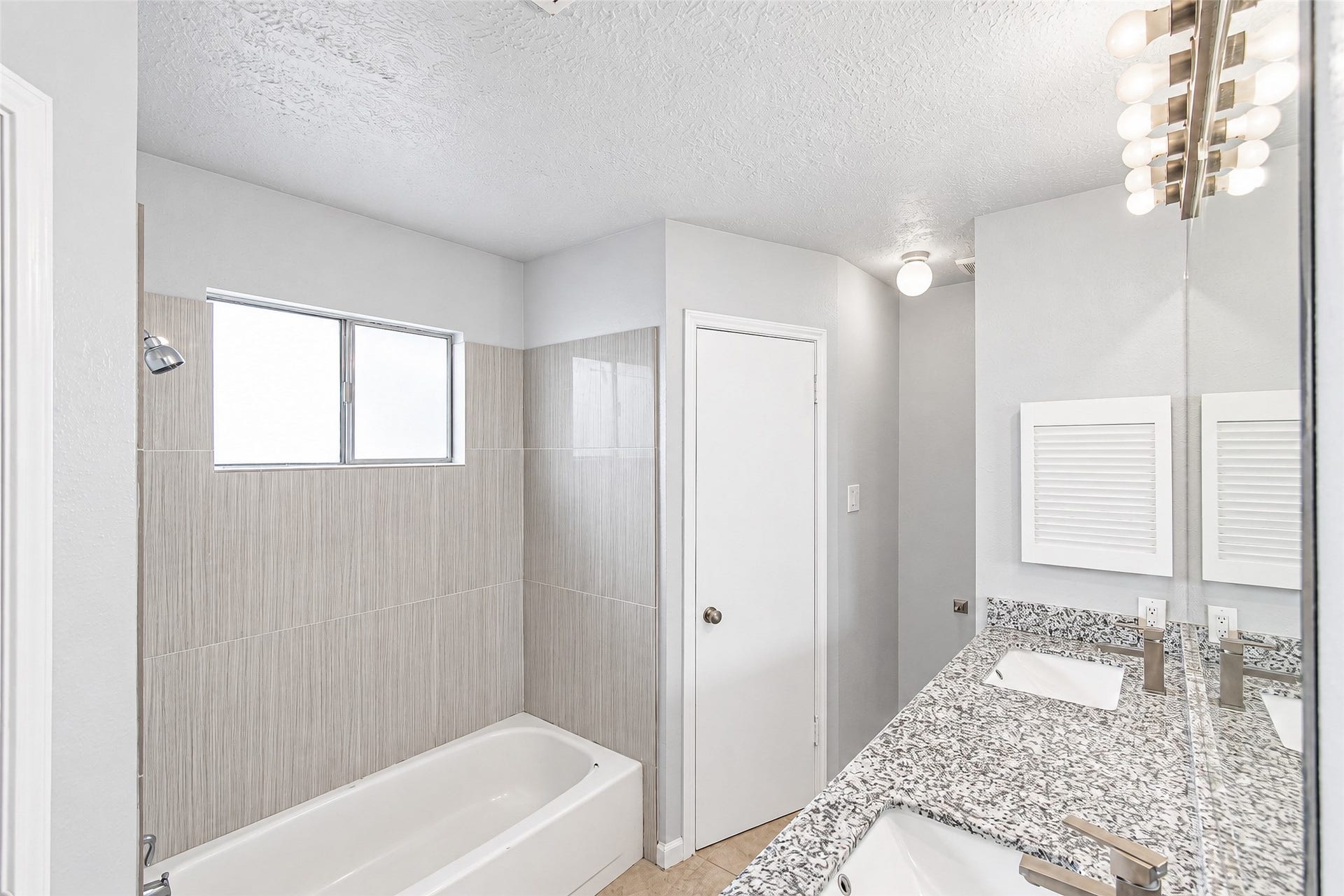 12027 Huntington Park Drive, Houston, TX 77099 Bright and modern bathroom featuring a stylish granite countertop, sleek fixtures, and a spacious bathtub with contemporary tile surround.