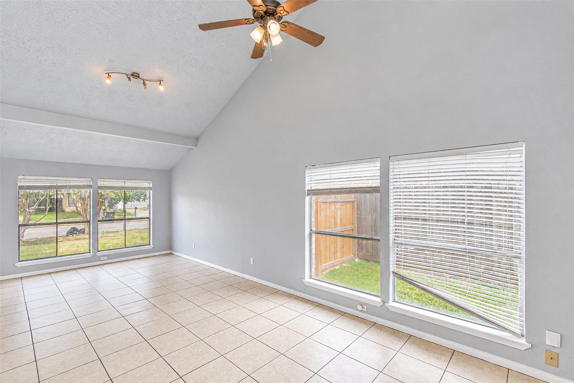 12027 Huntington Park Drive, Houston, TX 77099 Spacious living room with high vaulted ceilings, abundant natural light from large windows, and elegant tile flooring.