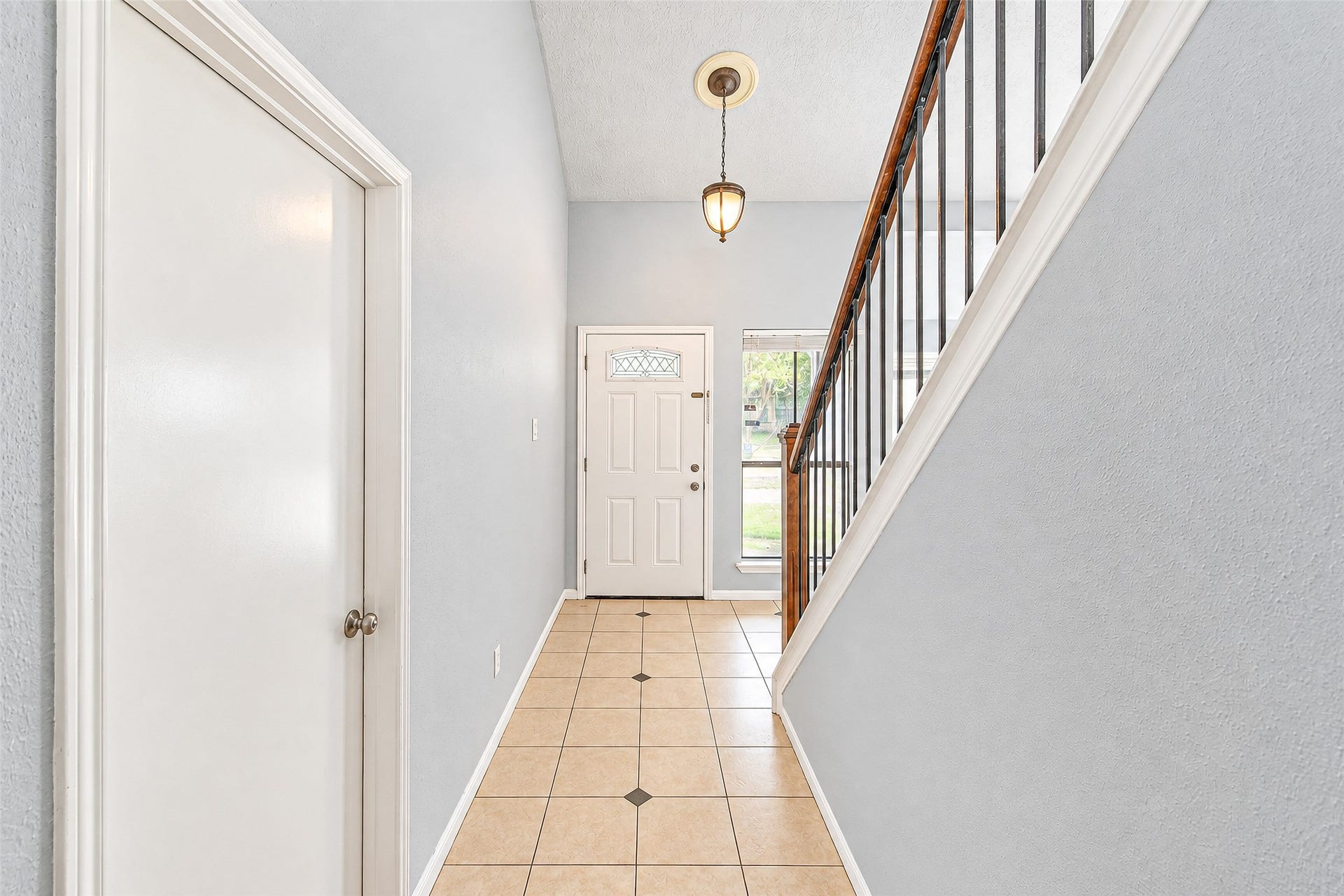12027 Huntington Park Drive, Houston, TX 77099 Inviting entryway with high ceilings, elegant tile flooring, and a charming staircase, offering a warm welcome to this beautiful home.