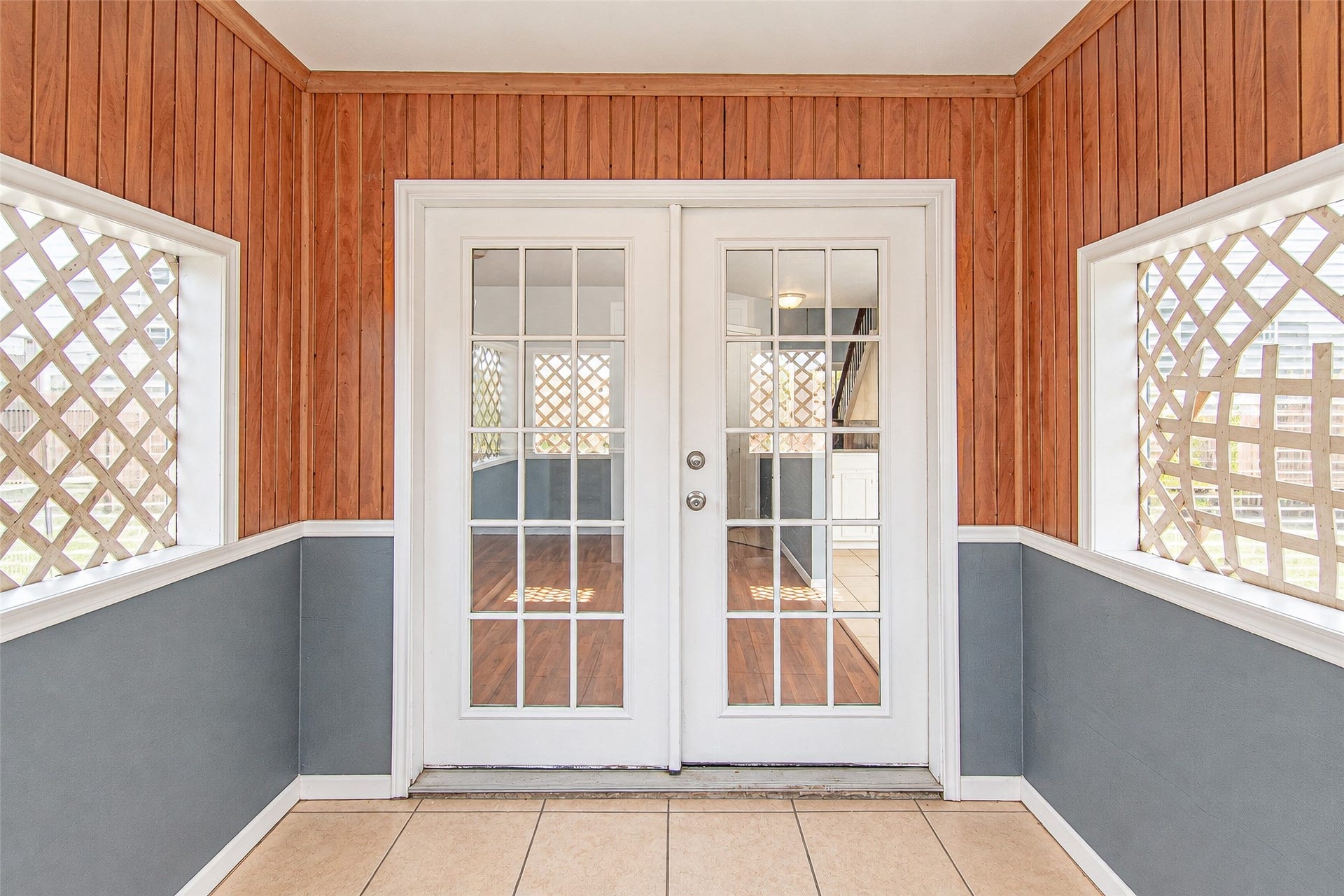 12027 Huntington Park Drive, Houston, TX 77099 Charming sunroom with warm wood paneling and elegant French doors, offering a cozy transition to the interior living space.