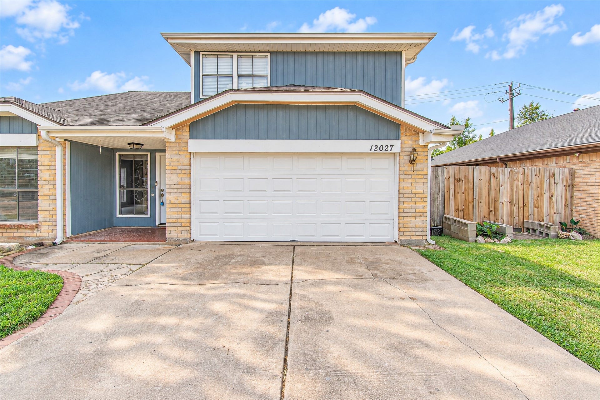 12027 Huntington Park Drive, Houston, TX 77099 Charming two-story home with a spacious driveway leading to a double garage, featuring a welcoming front entrance and well-maintained exterior.