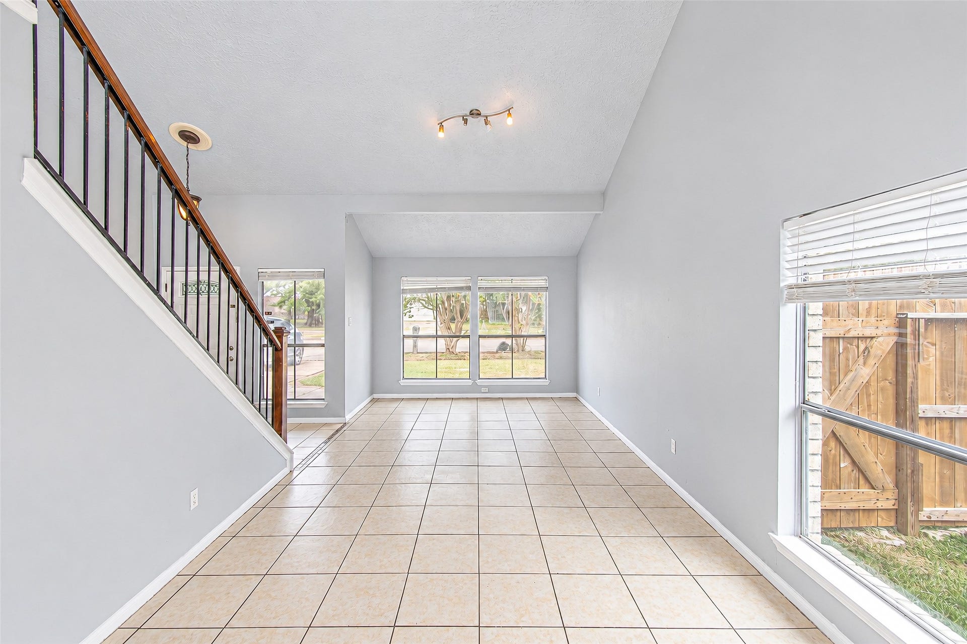 12027 Huntington Park Drive, Houston, TX 77099 Bright and airy living space with high ceilings, tiled flooring, and large windows offering abundant natural light.