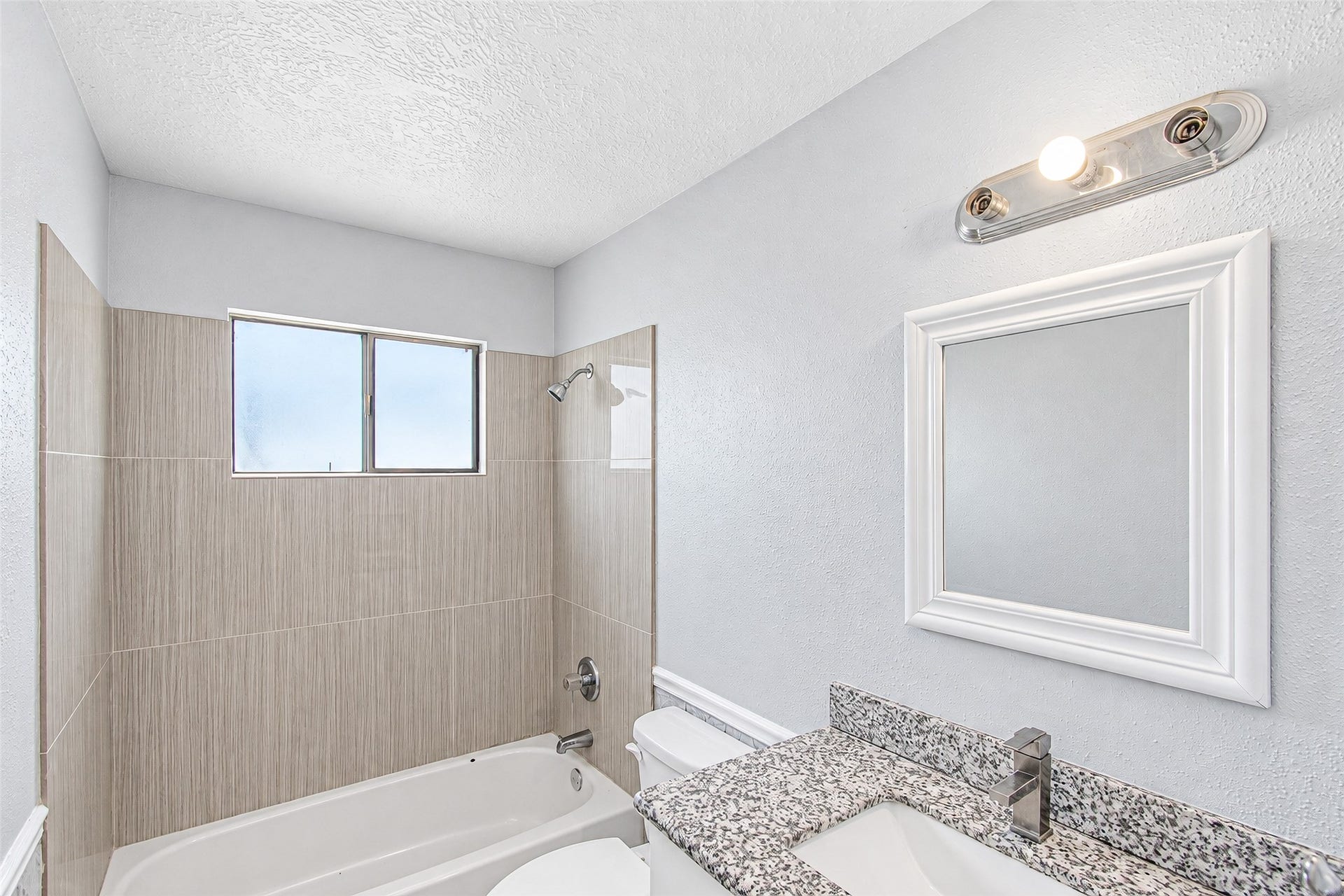 12027 Huntington Park Drive, Houston, TX 77099 Bright and modern bathroom featuring a sleek granite countertop, elegant tile backsplash, and a convenient shower-tub combo.